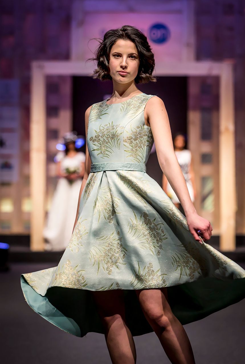 Una mujer con un vestido camina por una pasarela en un desfile de moda.