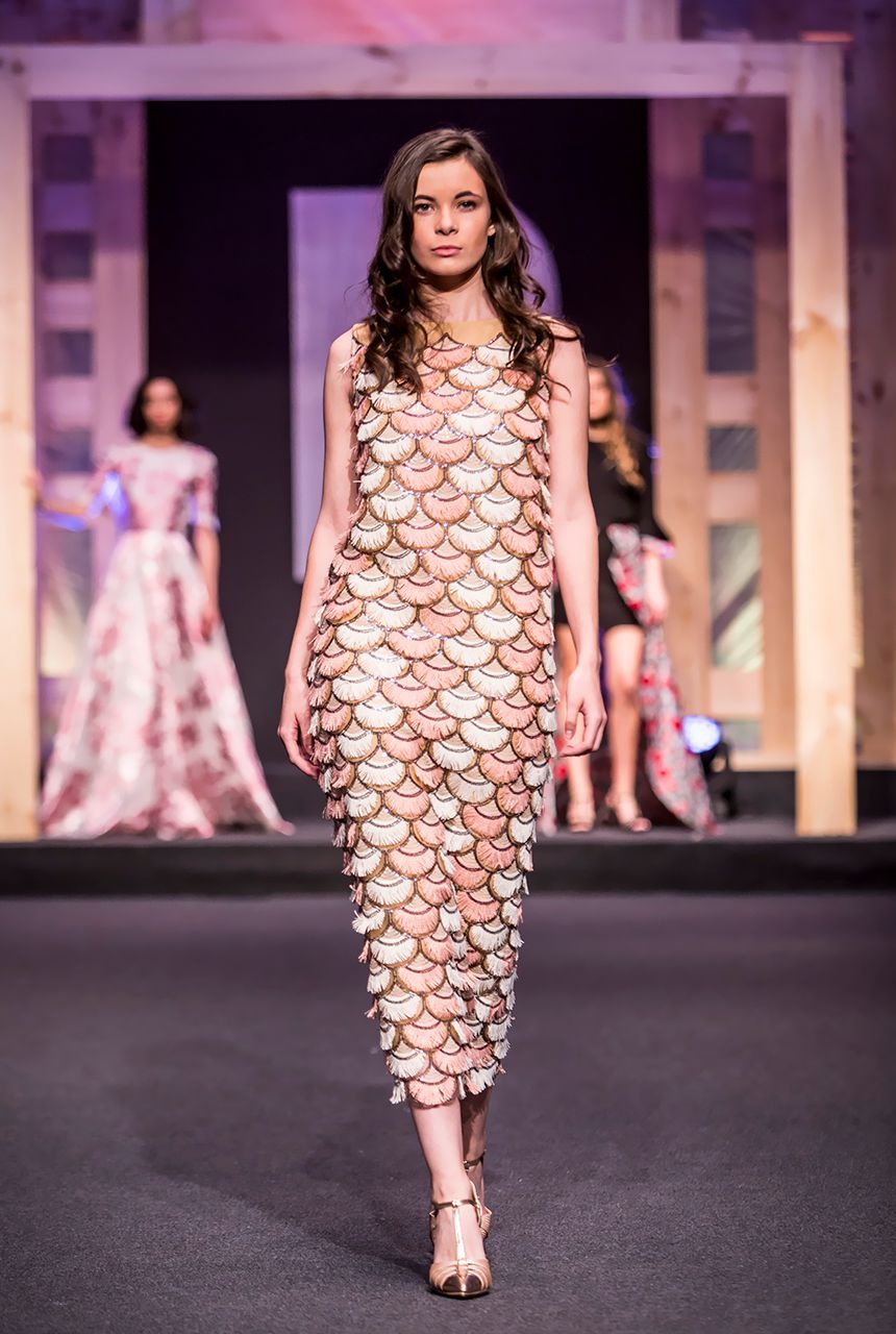 Una modelo camina por la pasarela en un desfile de moda con un vestido de escamas de pescado.