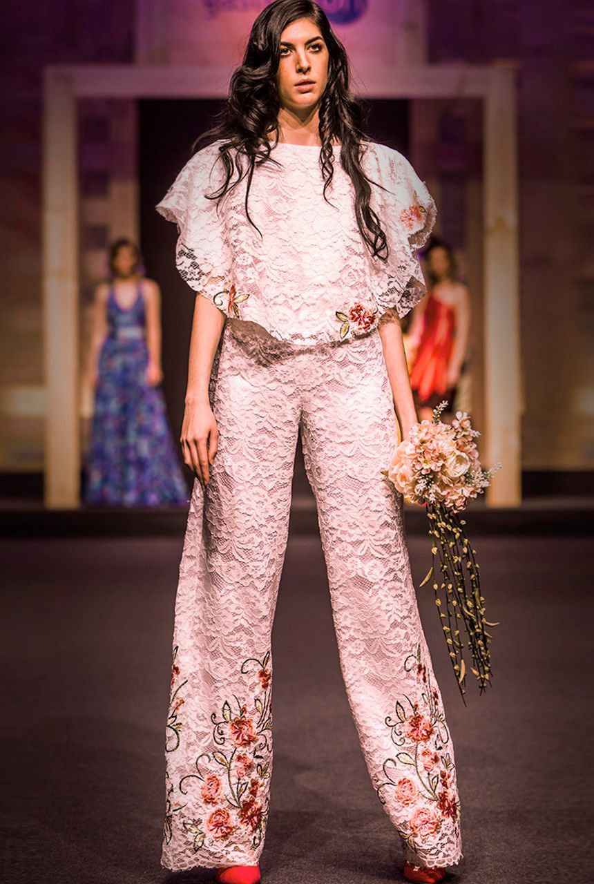 Una mujer camina por una pasarela sosteniendo un ramo de flores.