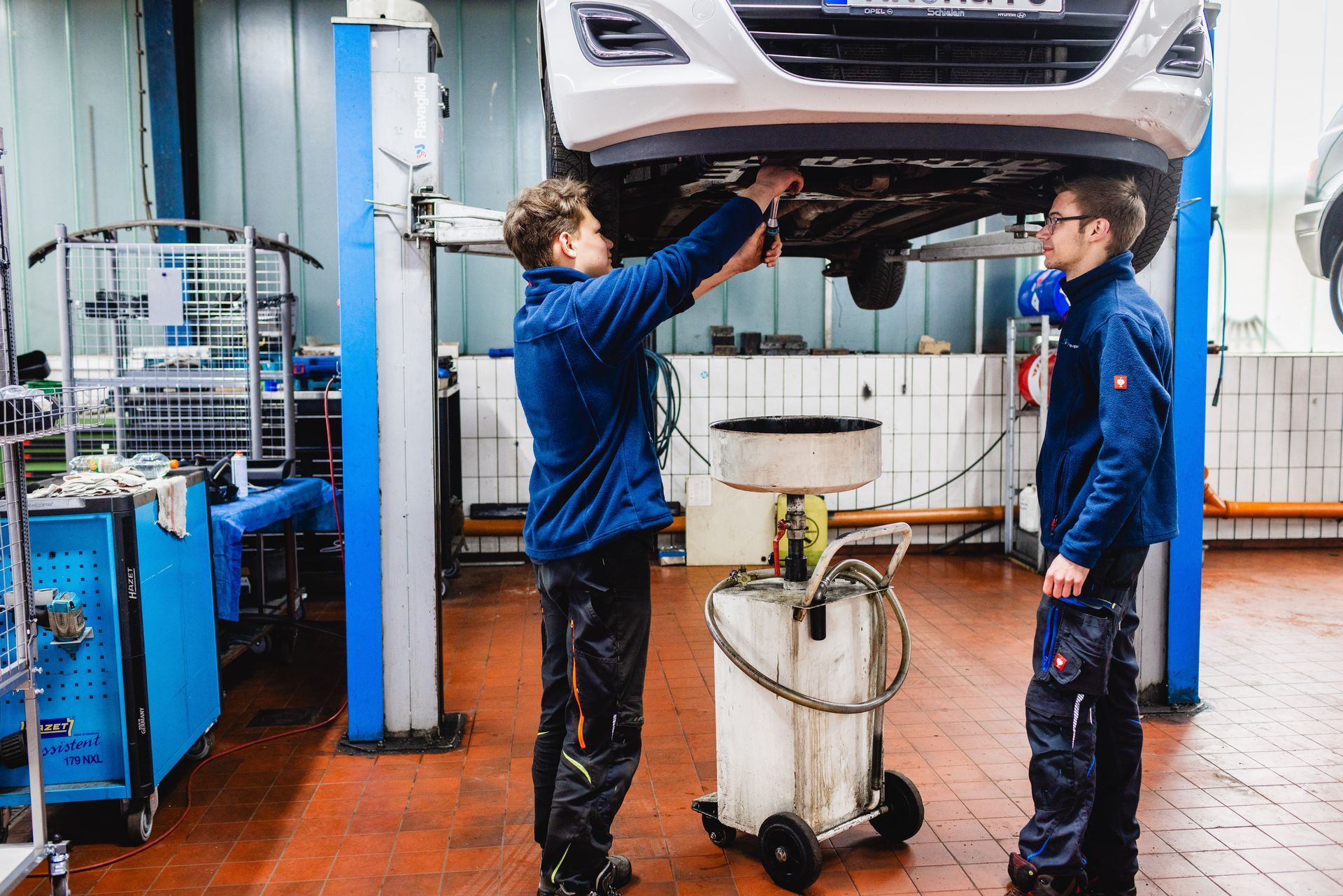 ein Mann arbeitet an einem Auto mit der Motorhaube offen