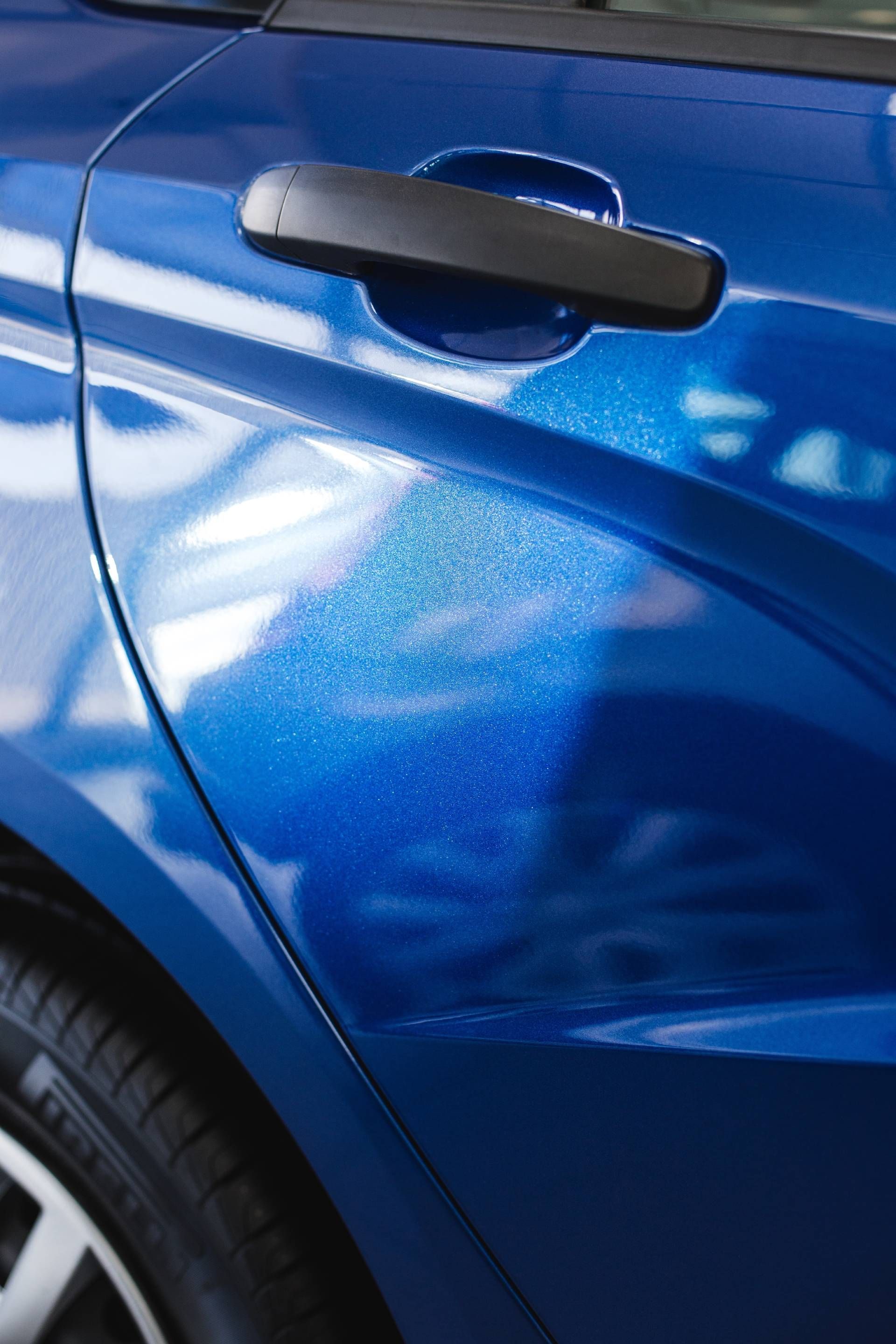 eine Nahaufnahme einer blauen Autotür mit einem schwarzen Griff