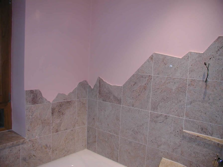 Badezimmerecke mit hellbrauner Fliesenwand, gezackter Kante und rosa Wand darüber.