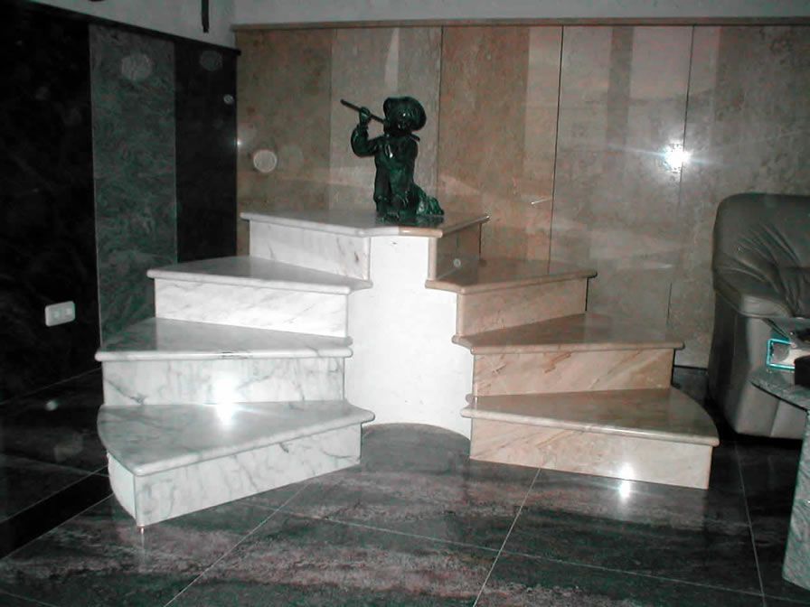 Marmortreppe mit der Statue eines Flöte spielenden Jungen; im Hintergrund verschiedene Marmorproben.