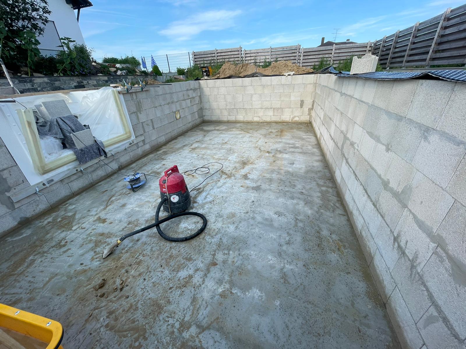 Leere Poolschale im Bau mit Wänden aus Schlackenblöcken und Betonboden.