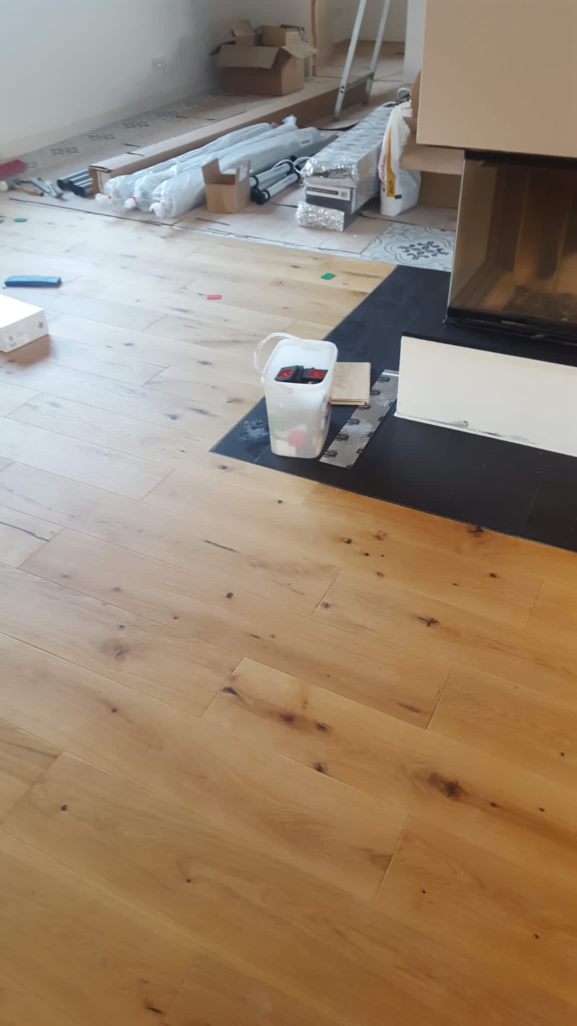 Heller Holzboden wird mit verschiedenen Materialien und Werkzeugen in einem Raum verlegt.