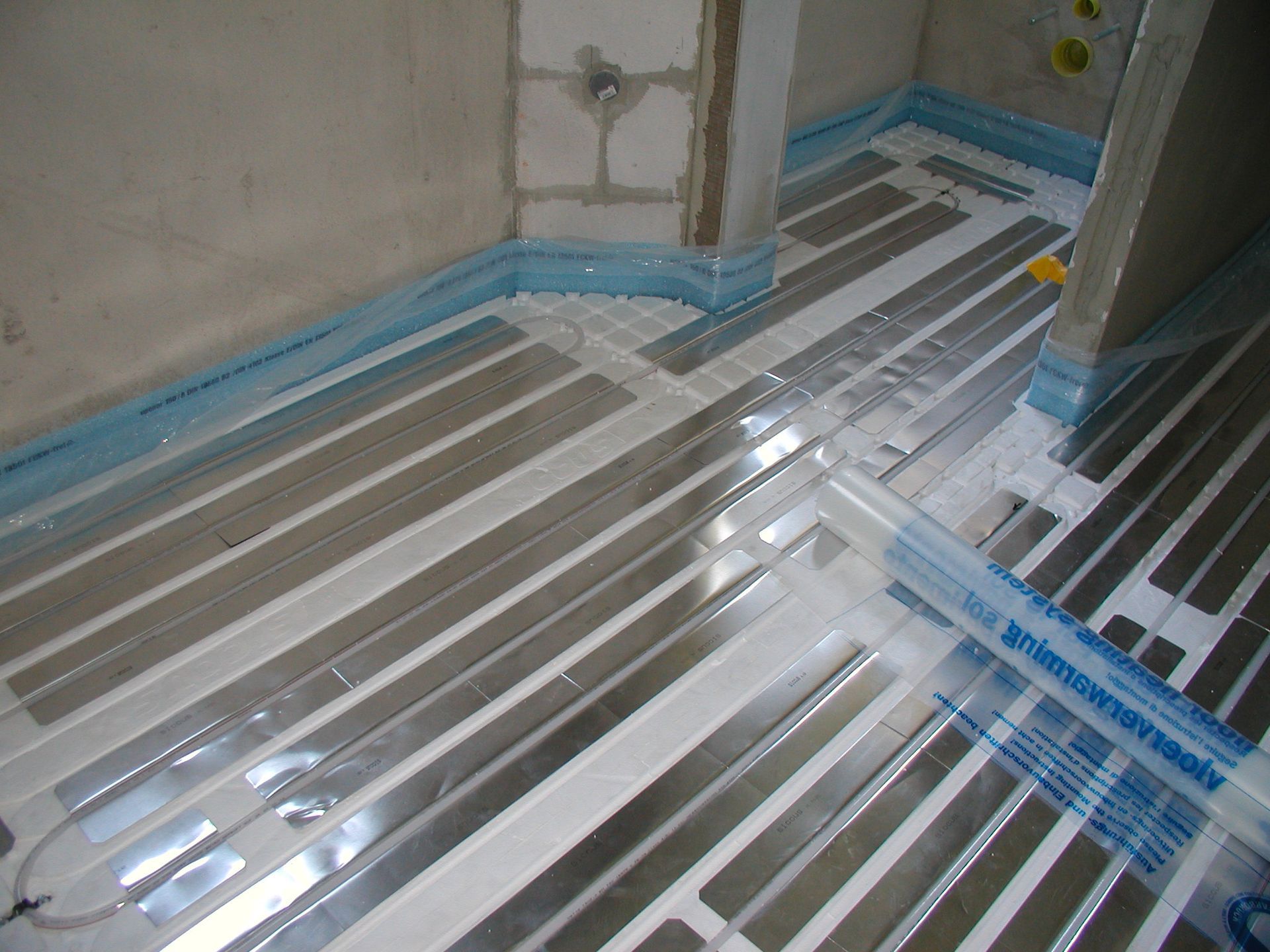 Fußboden mit Strahlungsheizung im Bau. Silberne Heizstreifen mit blauem Randband installiert.