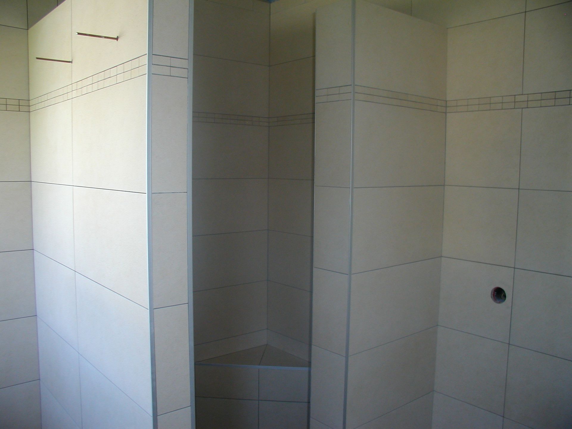 Gefliester Duschkabineninnenraum mit weißen Fliesen.