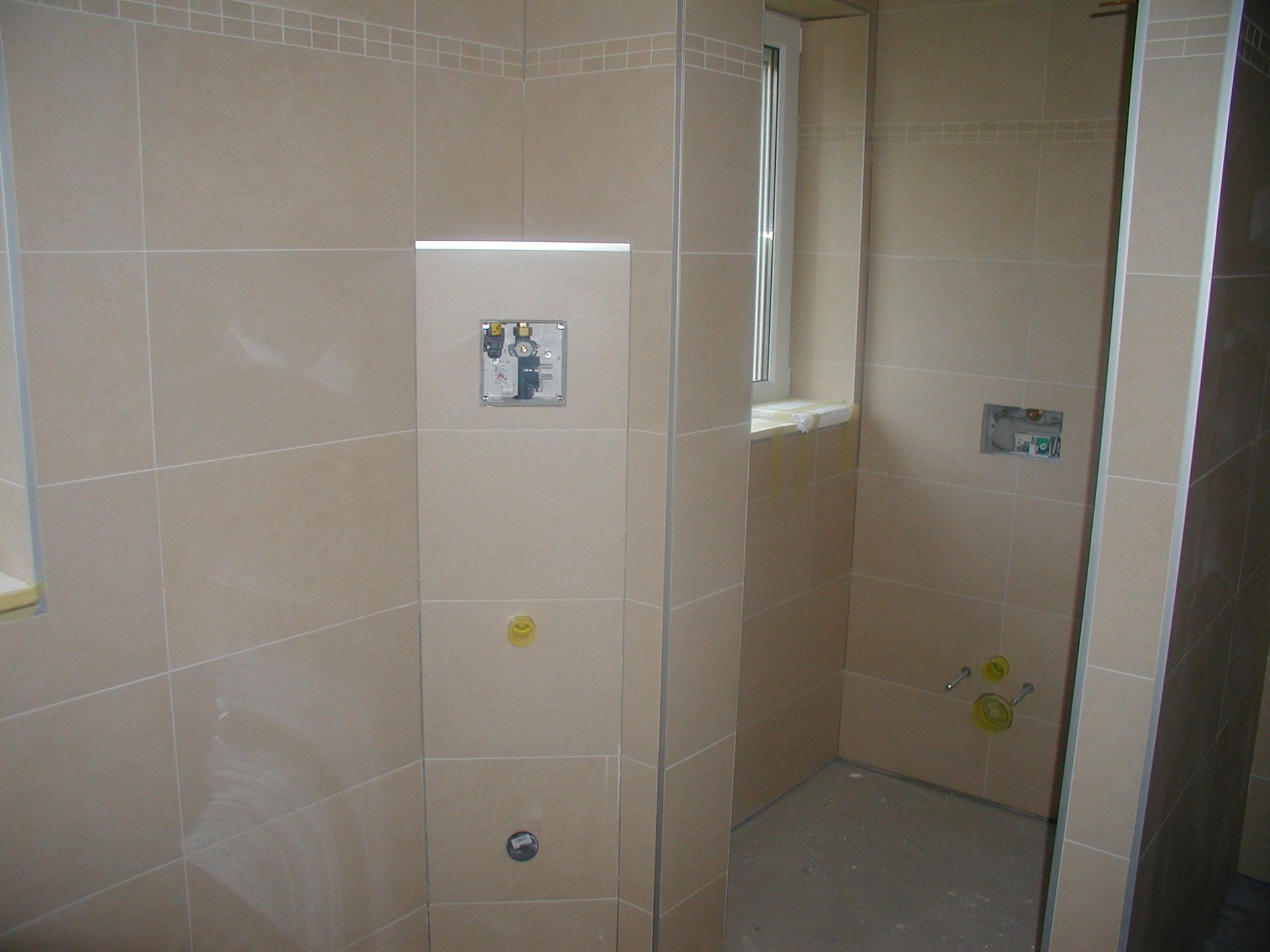 Beige gefliestes Badezimmer mit Toilettenspülung und Fenster.