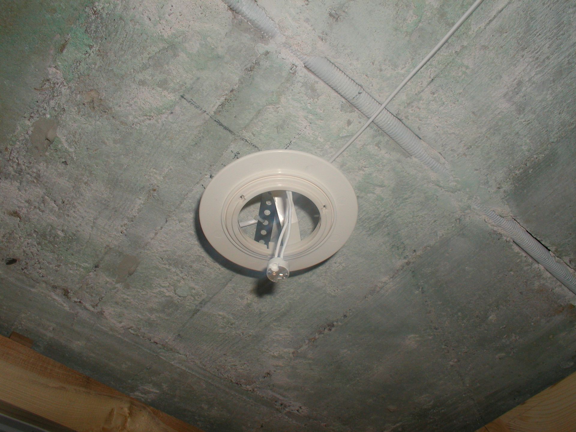 Decke mit einer Sprinkleranlage. Graue, strukturierte Oberfläche mit weißem Sprinklerkopf.