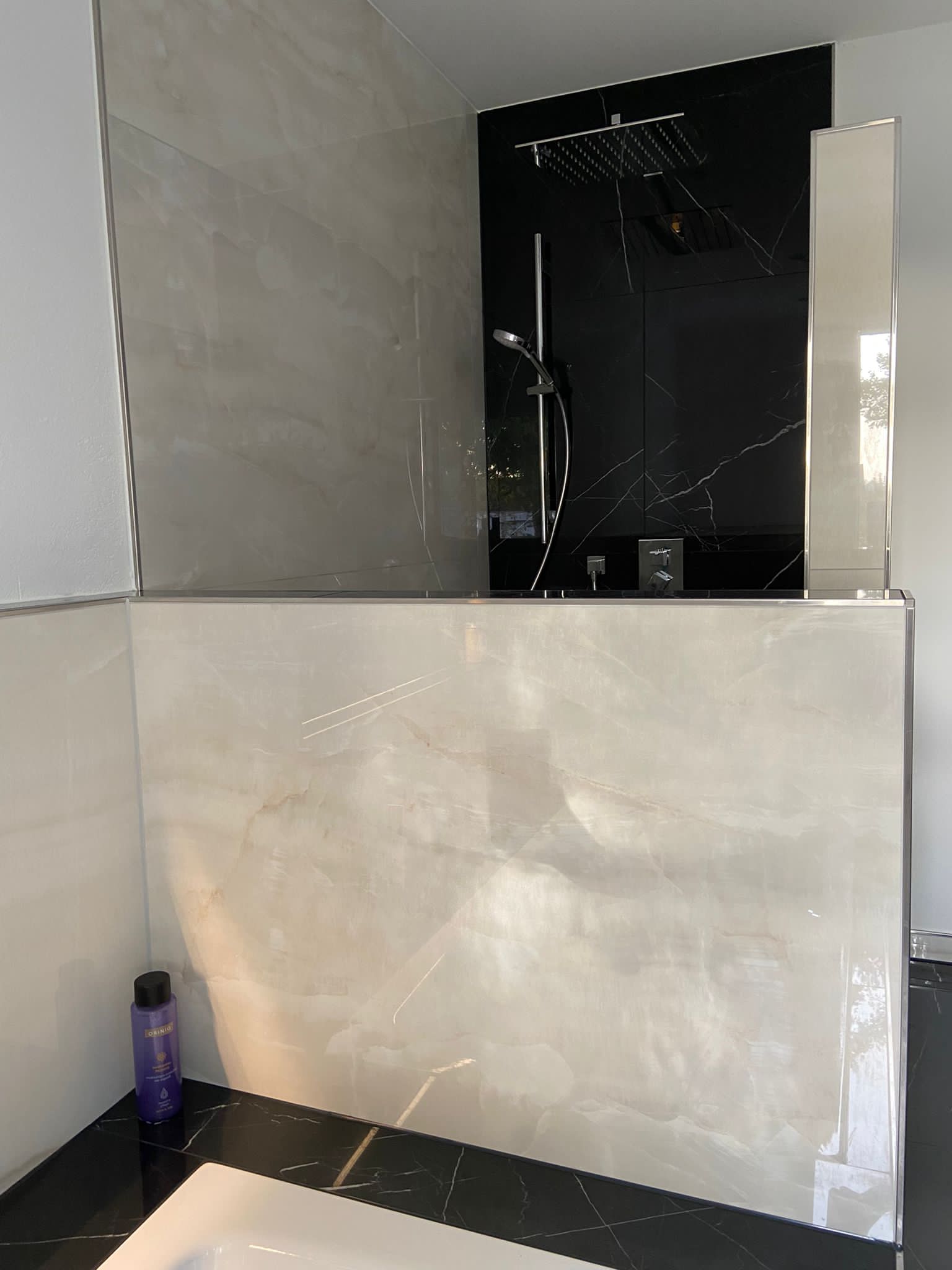 Moderne Badezimmerdusche mit schwarzen und grauen Fliesen.