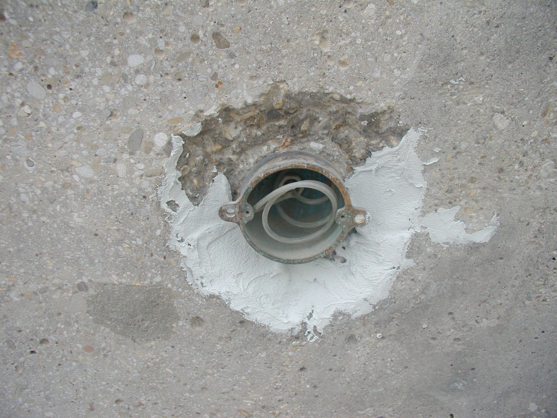 Metallrohr mit weißem Dichtmittel in Beton eingelassen.