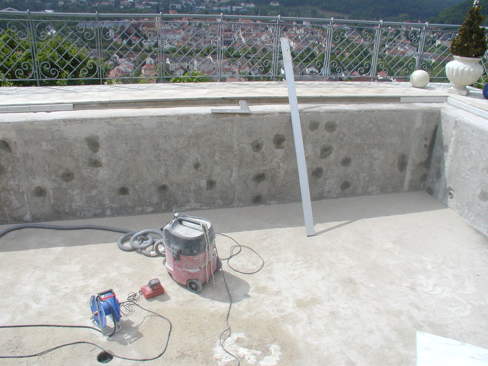 Pool im Bau mit Werkzeugen und einer entfernten Stadtlandschaft.