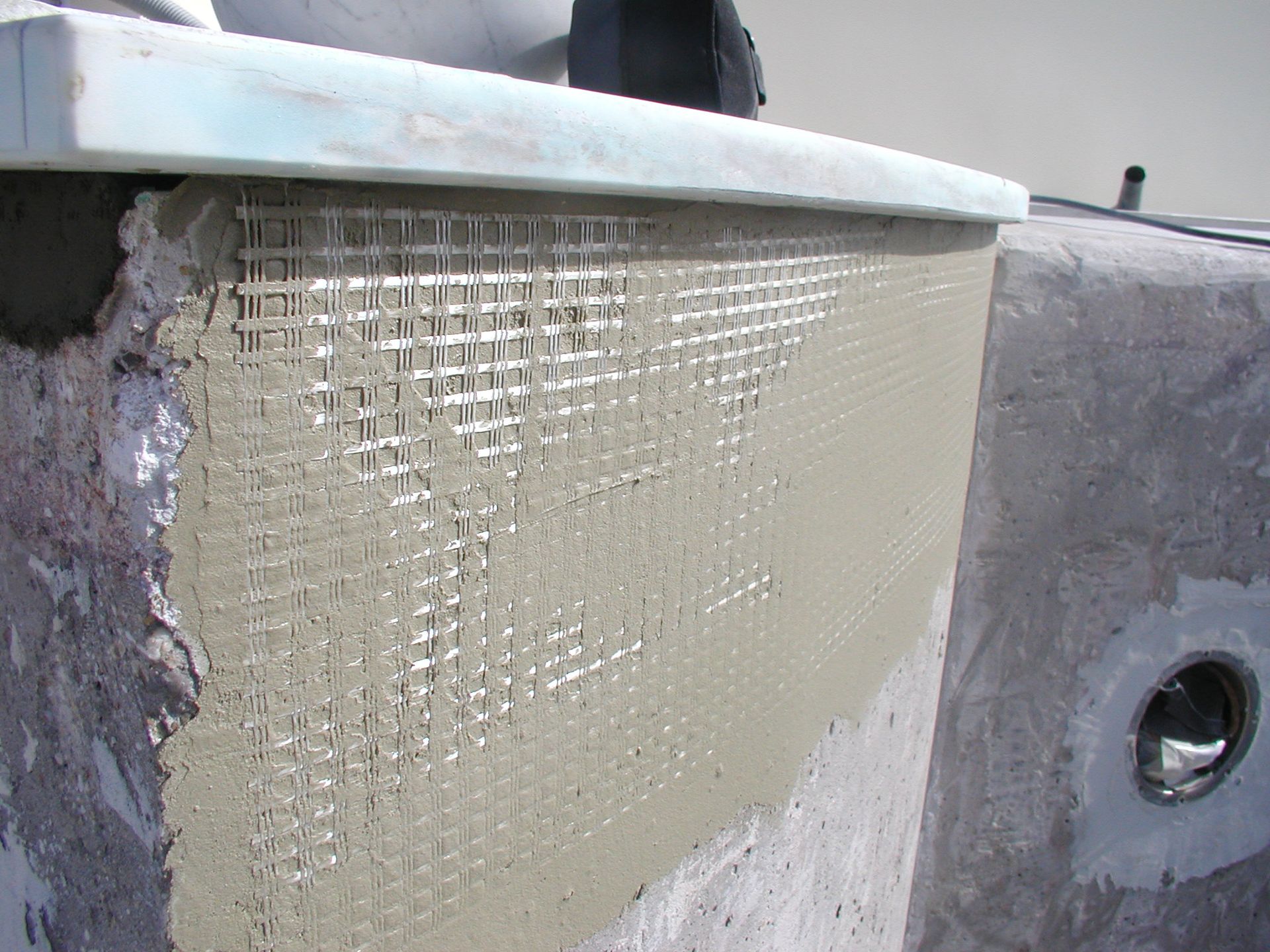 Grauer Zement mit Netz auf einer gebogenen Wand.