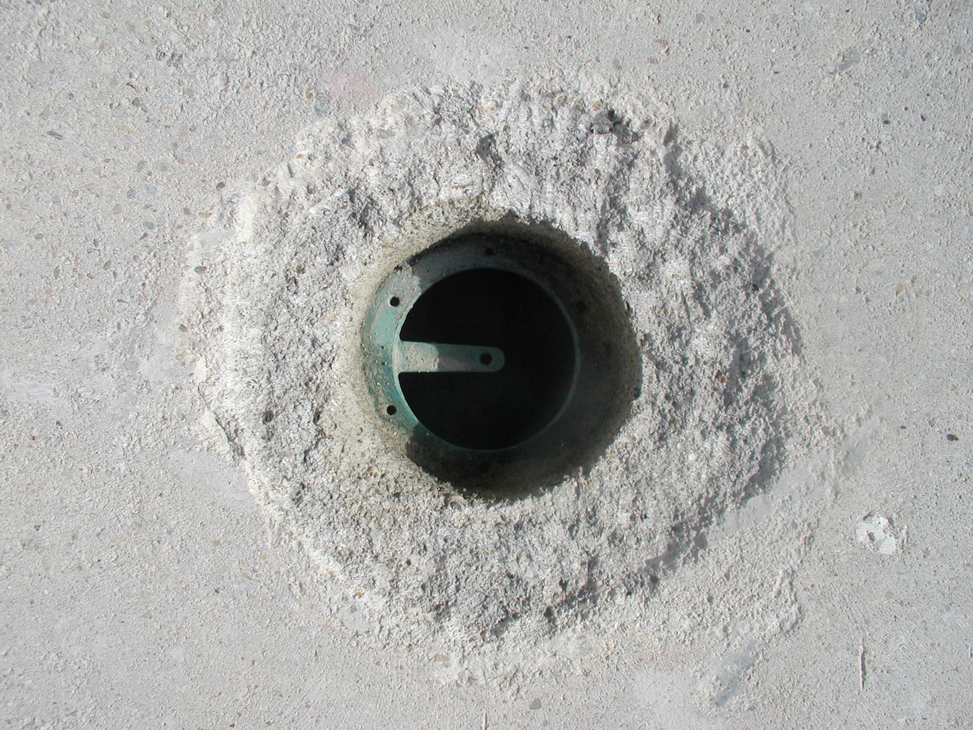 Loch im Beton mit einer Metallvorrichtung darin.