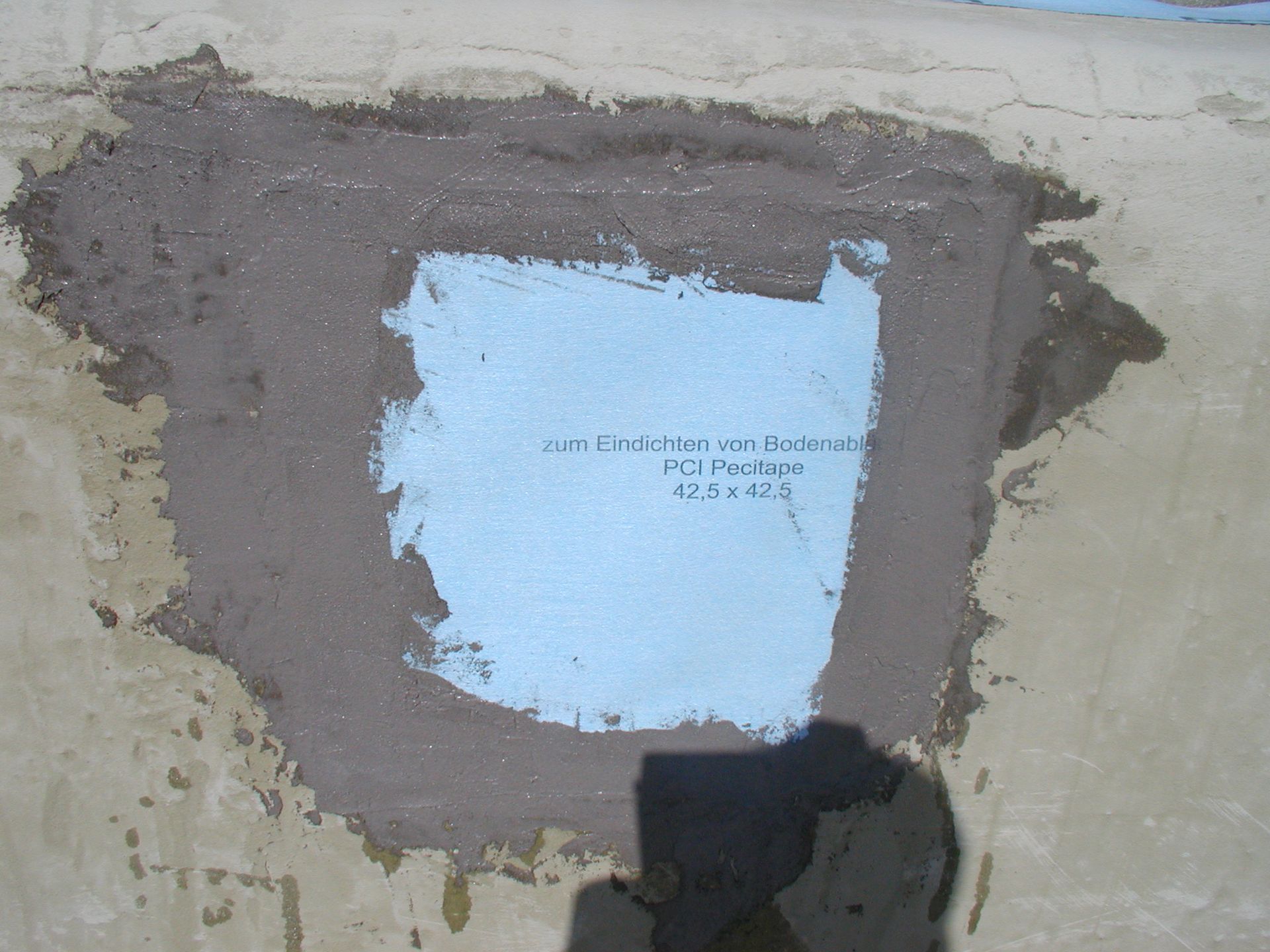 Eine Betonoberflächenreparatur mit blauer Schaumisolierung und grauem Zement.