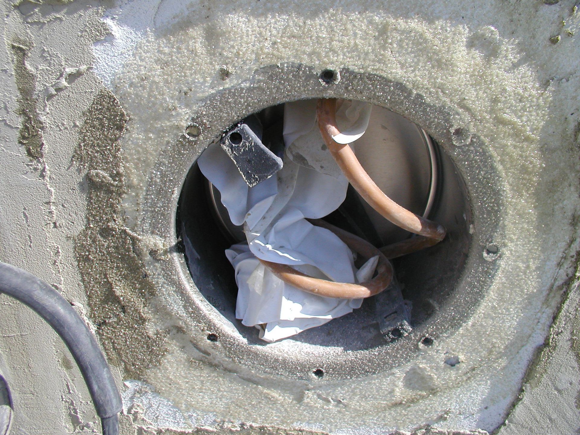 Ein metallener Zugangspunkt aus Beton mit Drähten und zerknülltem weißem Papier darin.