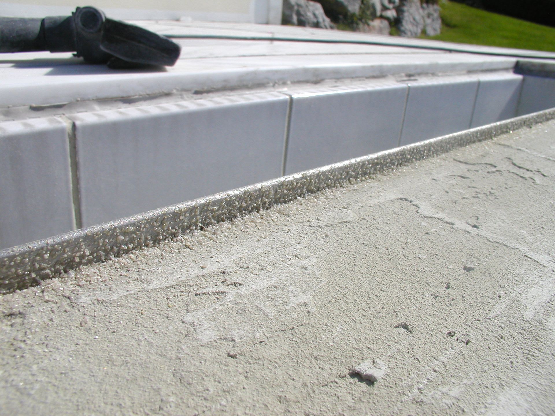 Nahaufnahme der gefliesten Stufen und der Metallkante, im Hintergrund eine Staubsaugerdüse.