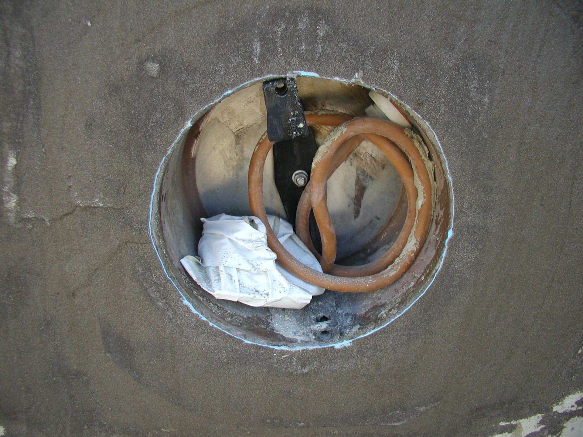 Loch in der Wand gibt den Blick auf elektrische Leitungen und Materialien frei. Graue Wand, kreisförmige Öffnung.