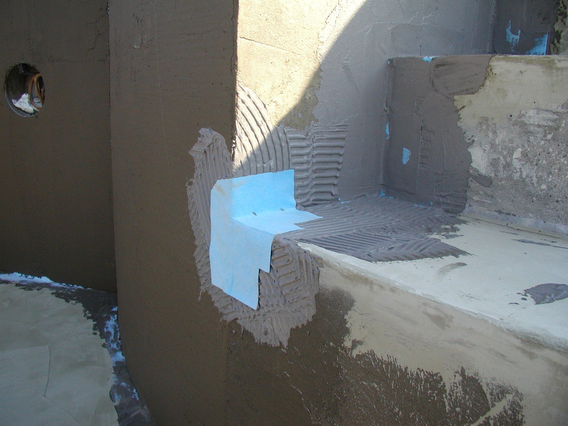 Poolkonstruktion: Blaue Eckabdeckung installiert, Stufen und Wand mit feuchtem Zement umgeben.