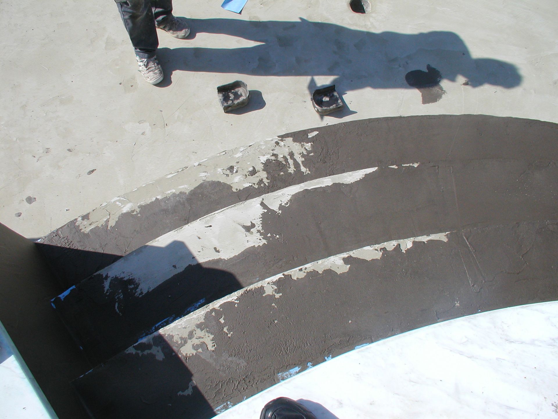 Dunkel gestrichene Poolstufen mit abblätternder Farbe; Menschen stehen in der Nähe.