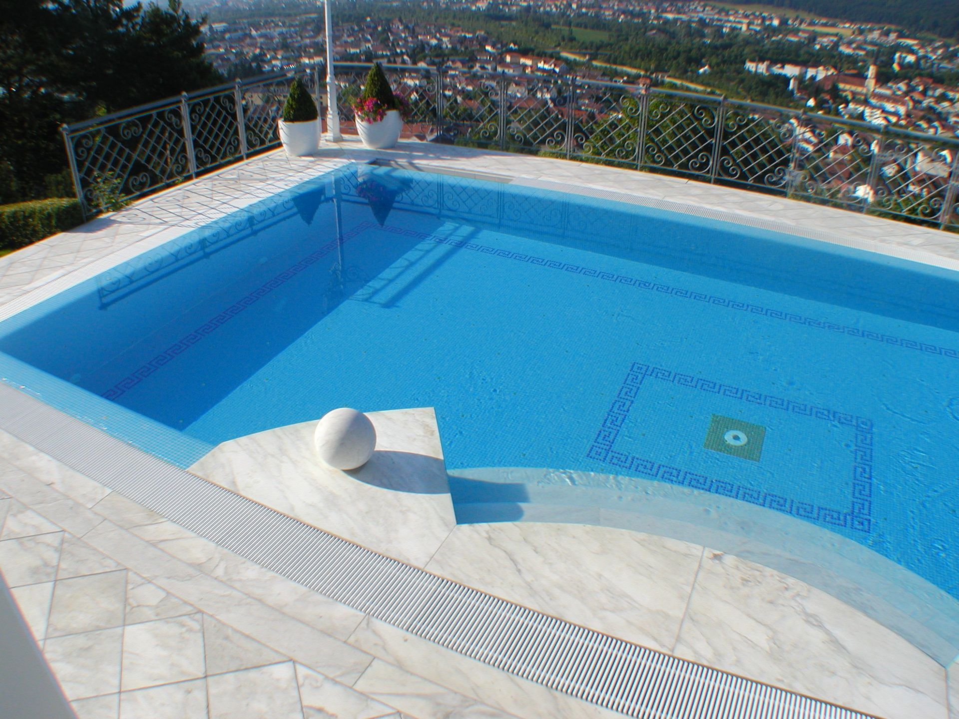 Swimmingpool mit Blick auf die Stadtlandschaft. Blaues Wasser, weiße Fliesen, sonnige Lage.