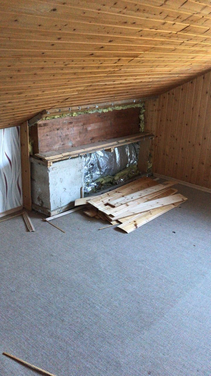 Dachbodenzimmer im Bau. Sichtbare Isolierung, Holzbretter und Verkleidung an der schrägen Decke.