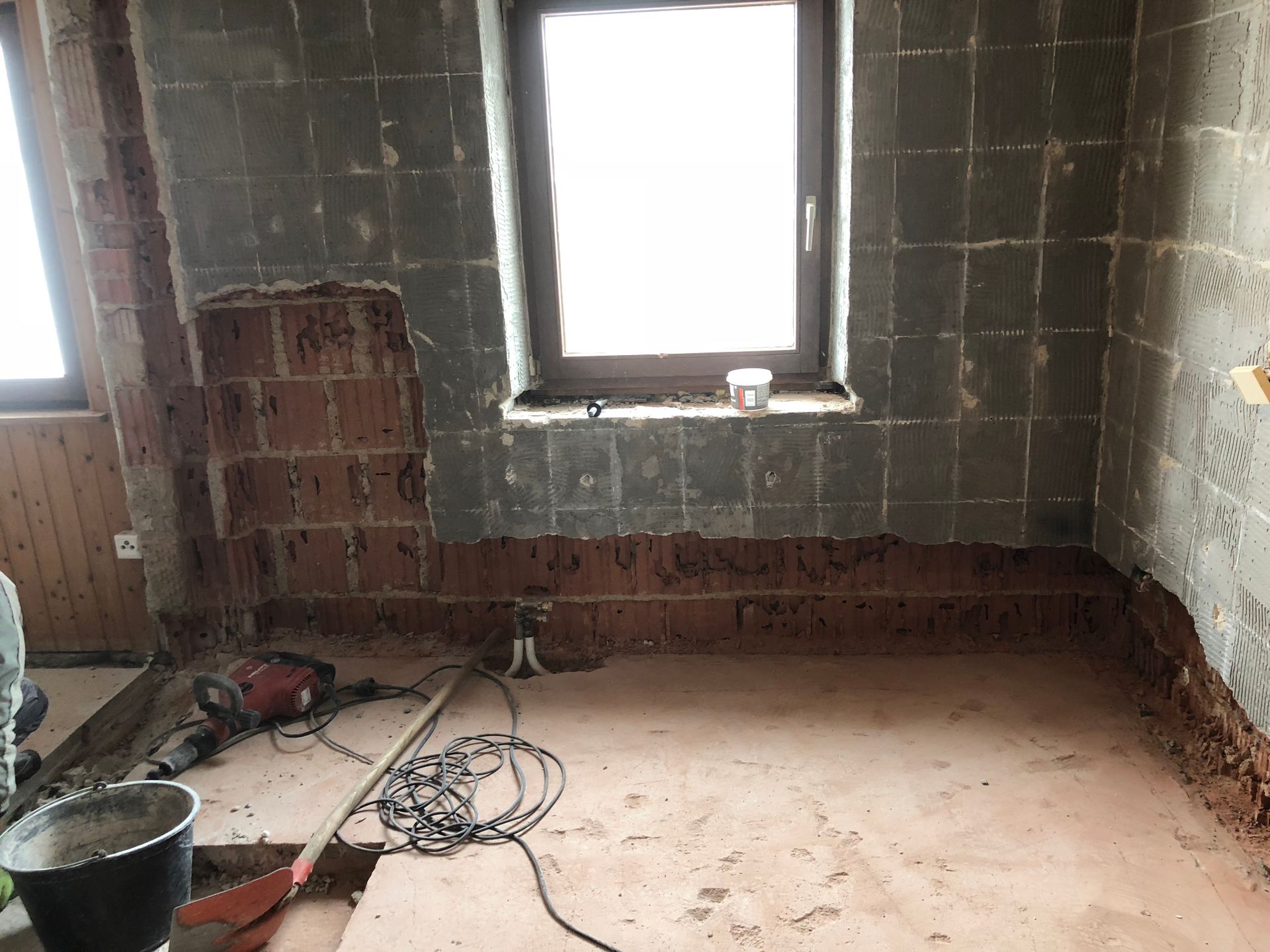 Renovierung des Innenraums. Die Wände sind mit Sichtziegeln gefliest. Fenster in der Mitte. Bauwerkzeuge auf dem Boden.