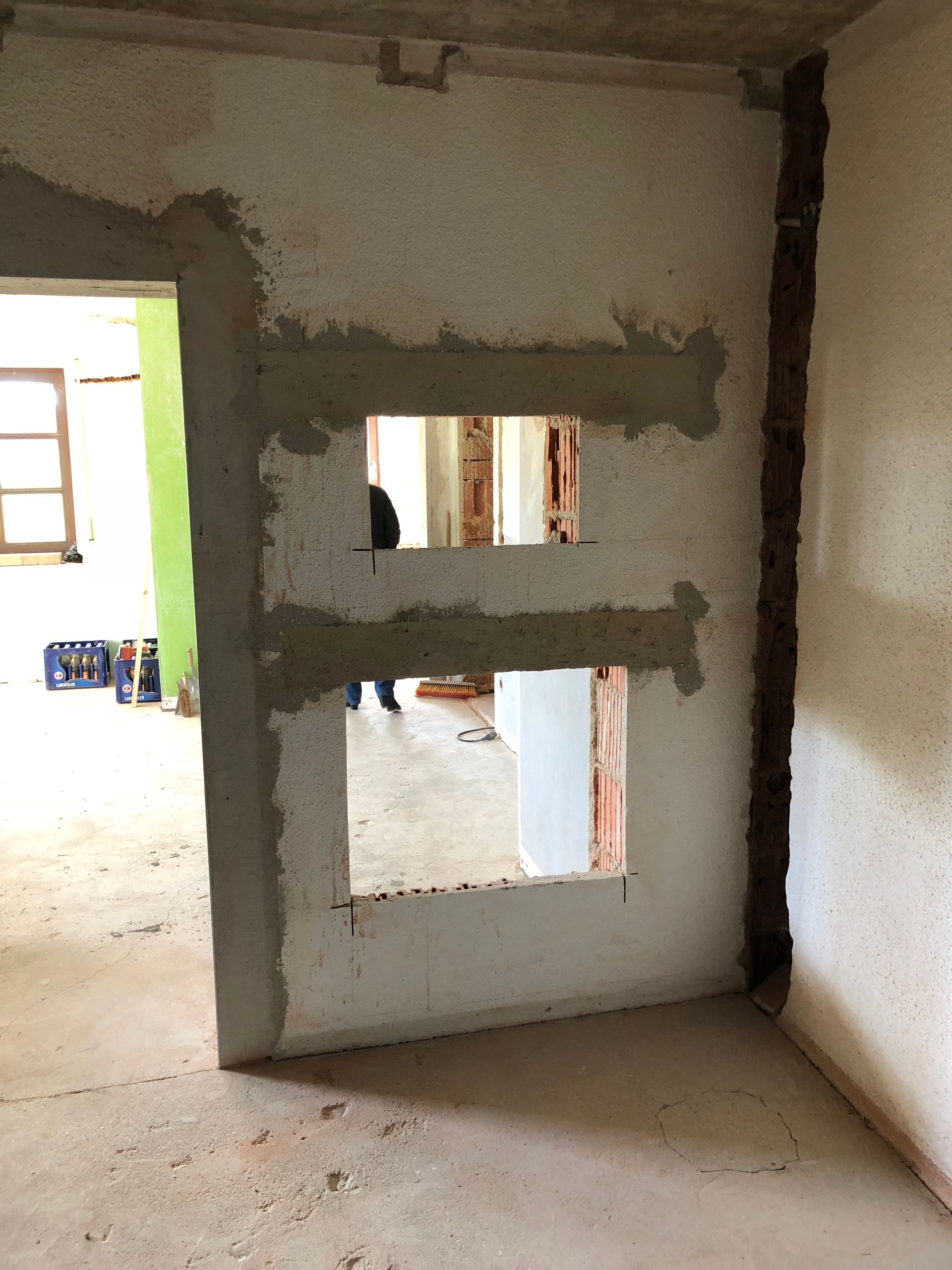 Wand mit zwei rechteckigen Öffnungen, Türöffnung links, Baustelle.