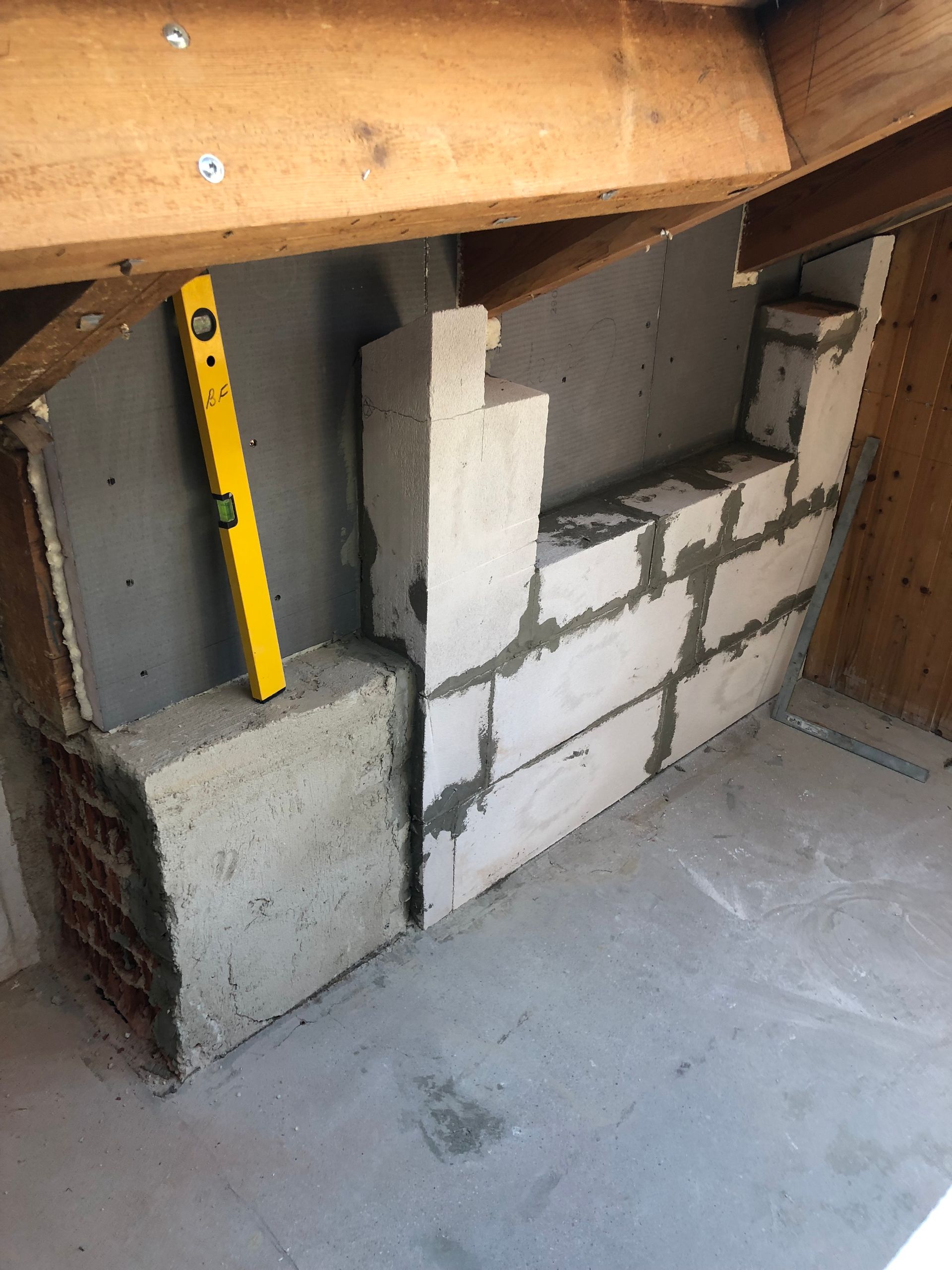 Ziegel- und Betonkonstruktion in einem Dachgeschoss; an einer Wand wird eine Wasserwaage verwendet.
