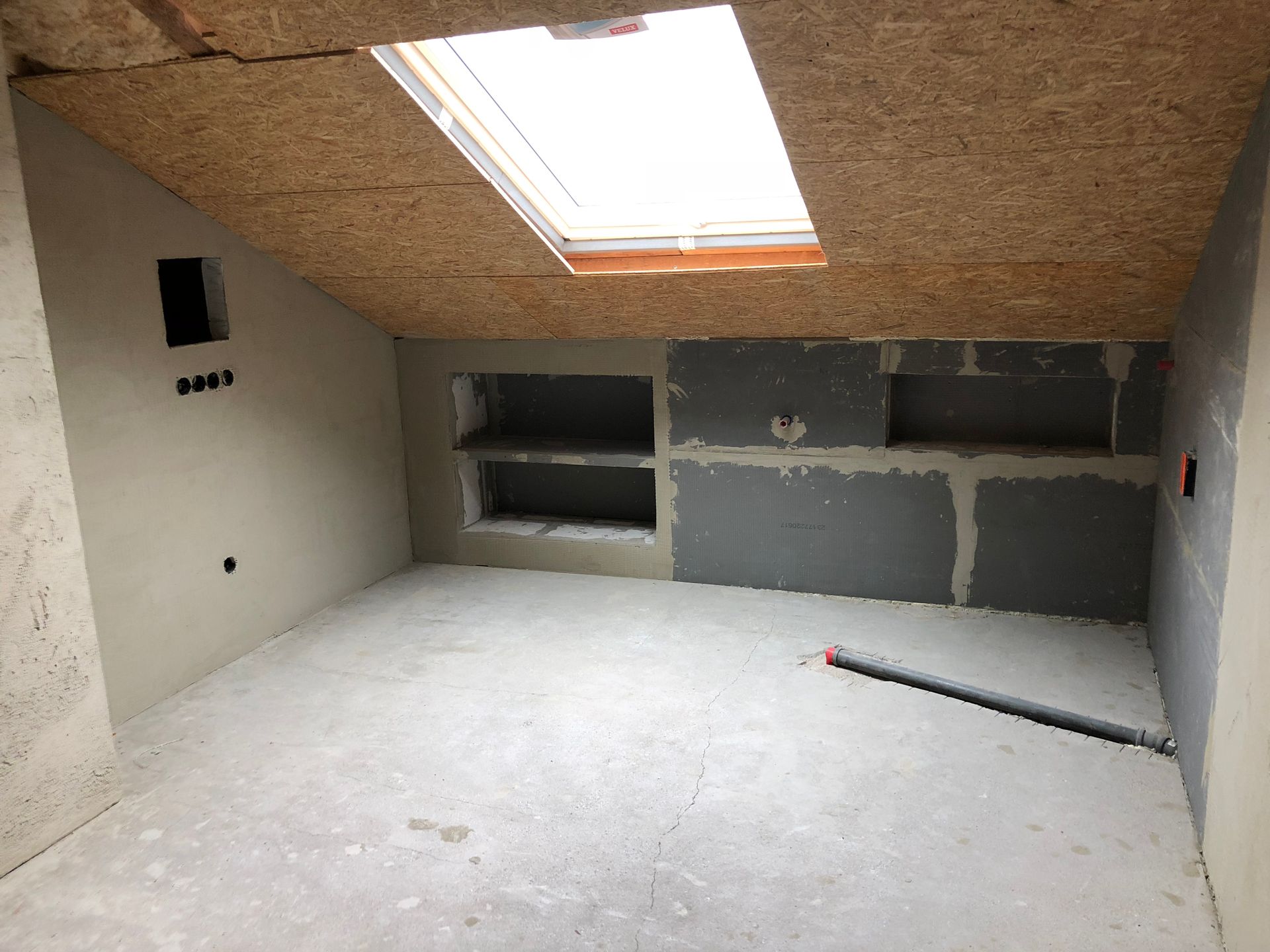 Im Bau befindlicher Raum mit Oberlicht, eingebauten Regalen und freiliegenden Leitungen.