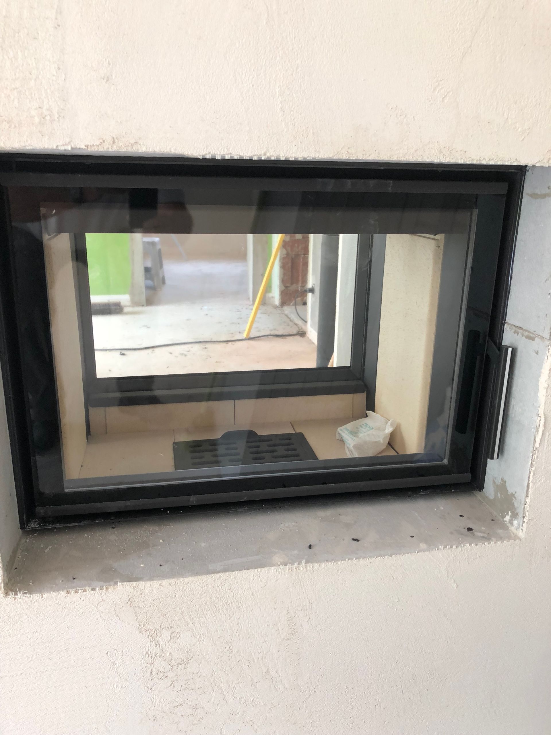 Ein Kamin mit geschlossener Glastür, eingebaut in eine helle Wand.