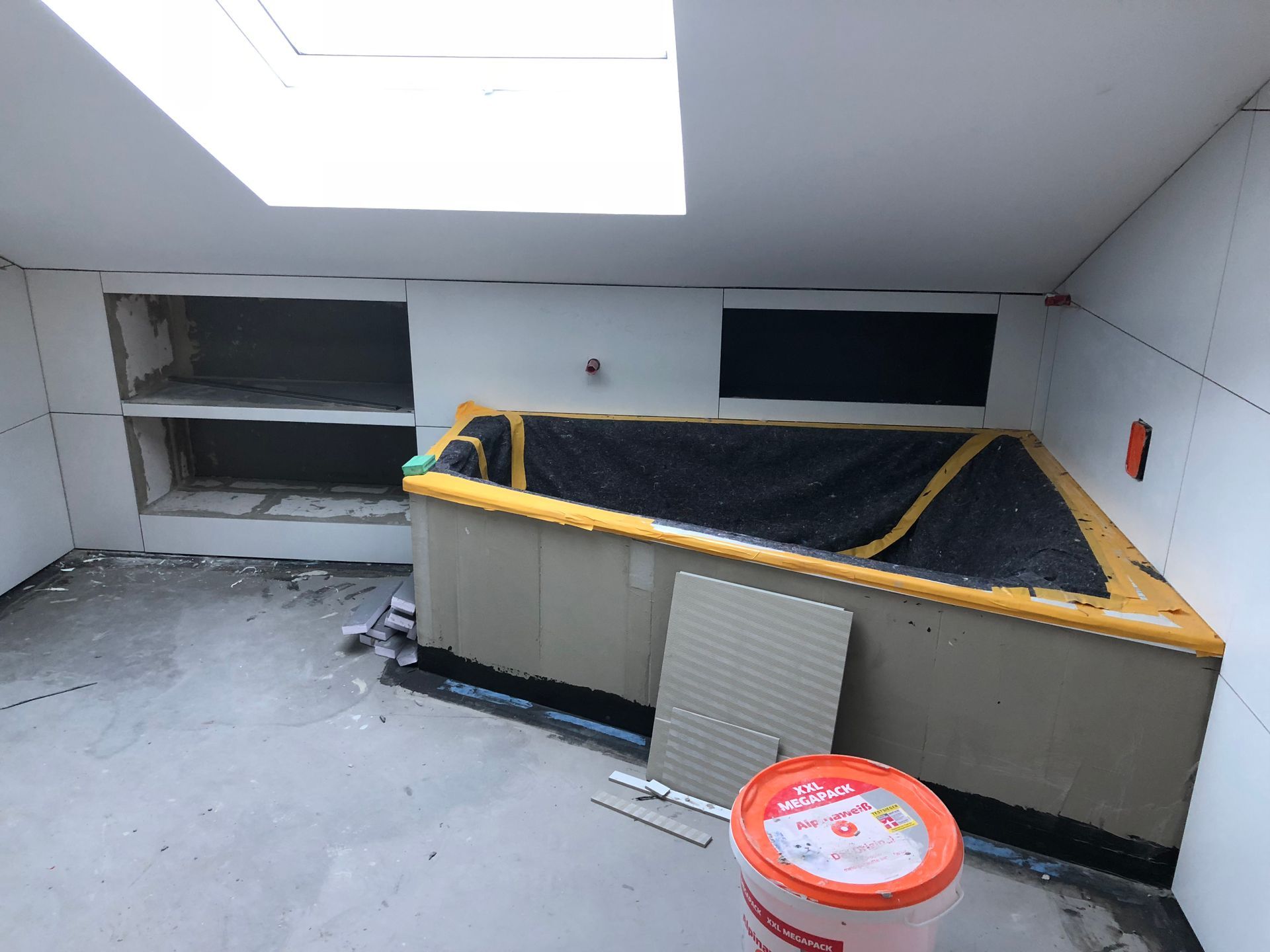 Badezimmer im Bau; Badewanne, Regale, ein Oberlicht und Trockenbau.