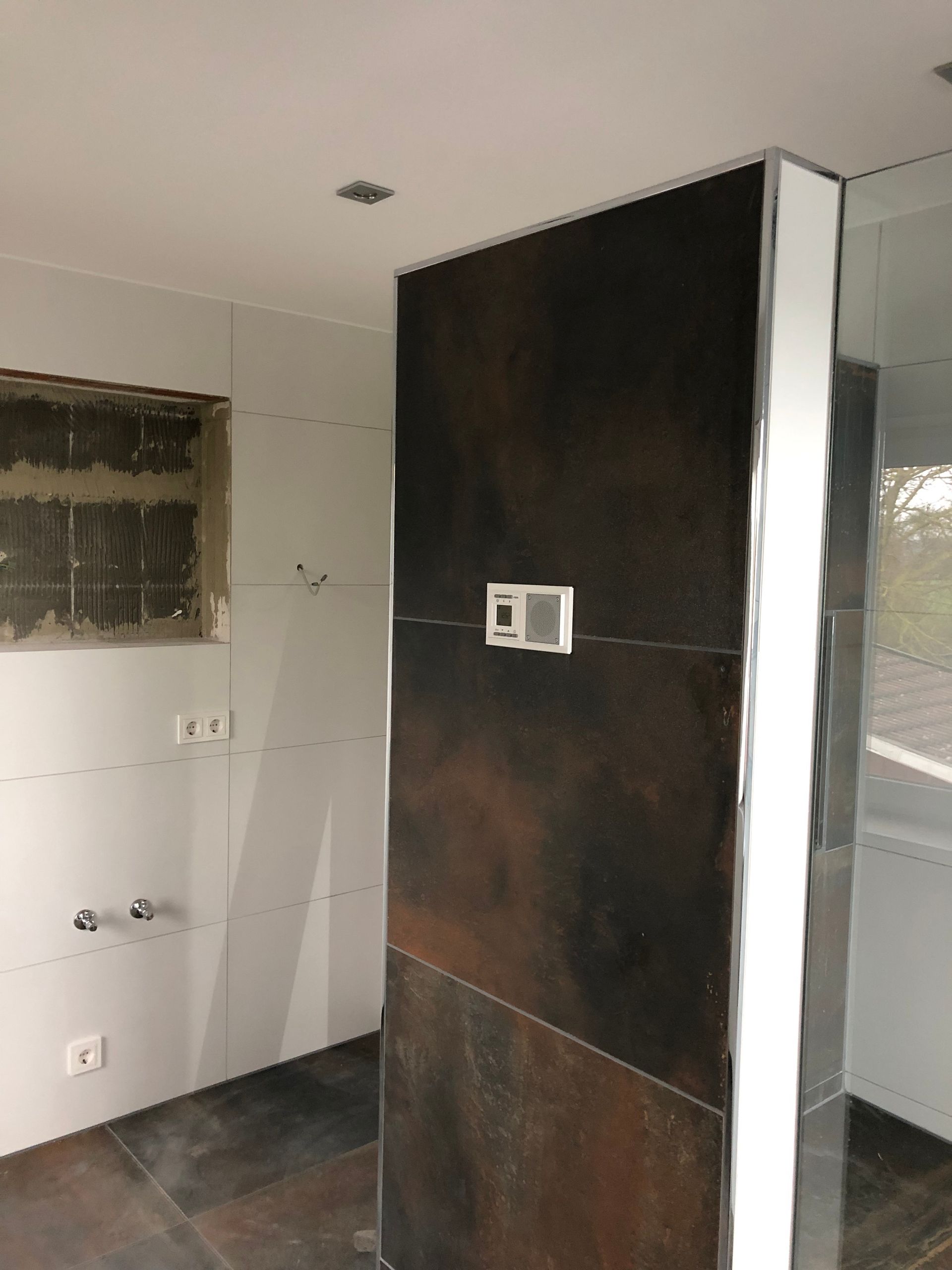 Badezimmer im Bau mit dunkler strukturierter Wand und weißen Zierleisten.