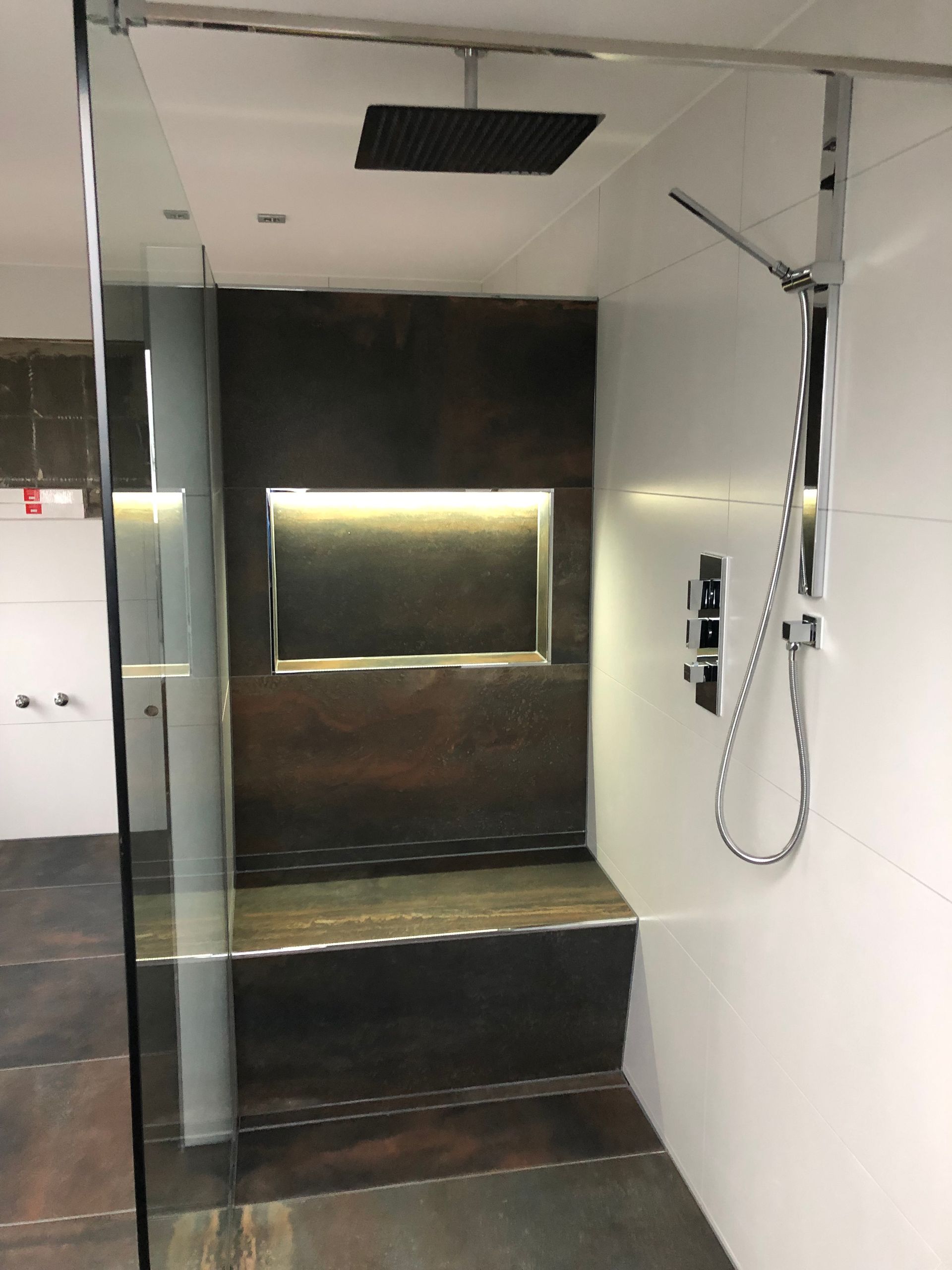 Moderne Dusche mit dunkler Akzentwand, Bank und Regenduschkopf.