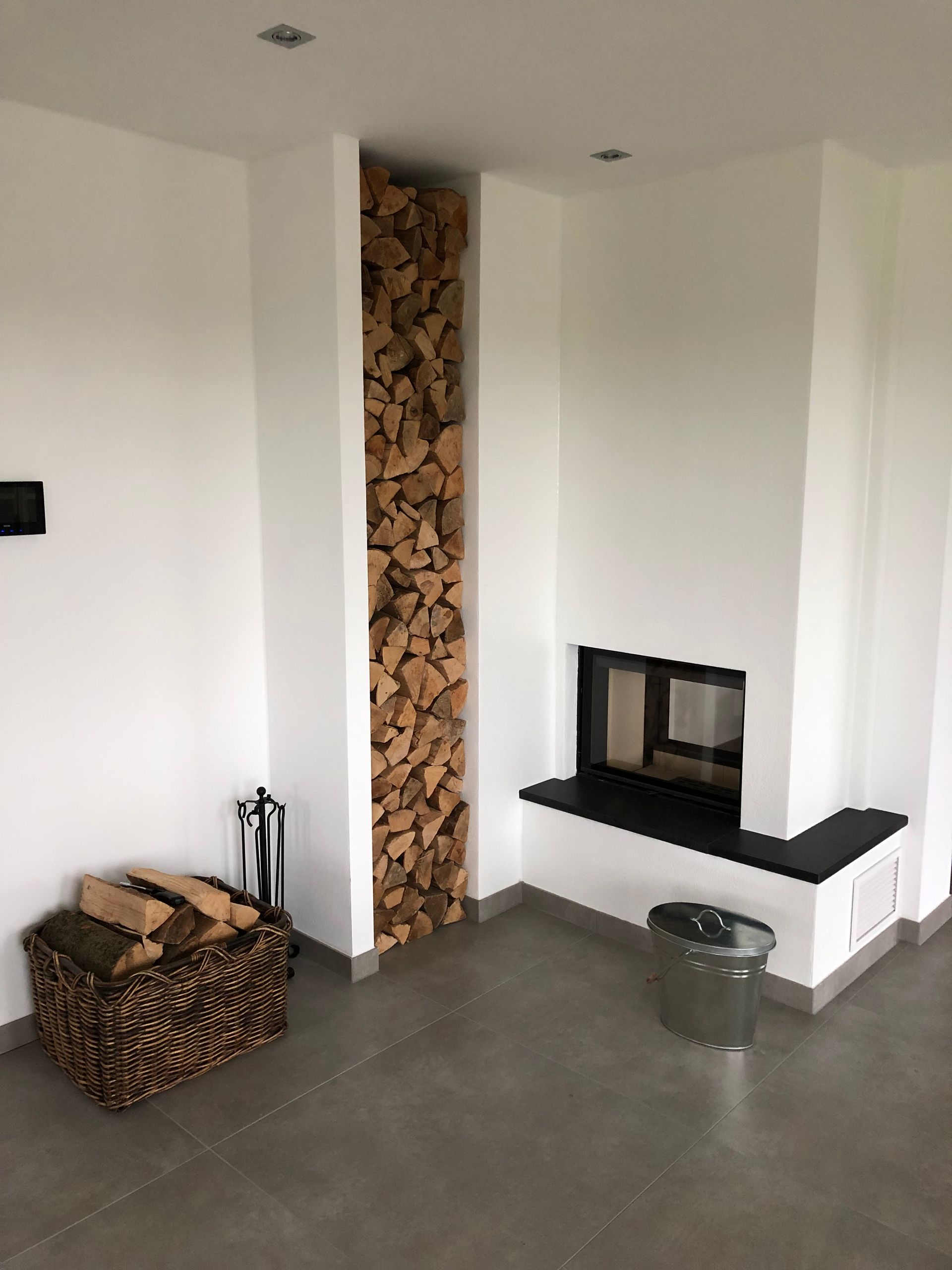 Moderner Raum mit Kamin, Holzlagernische und Holzkorb.