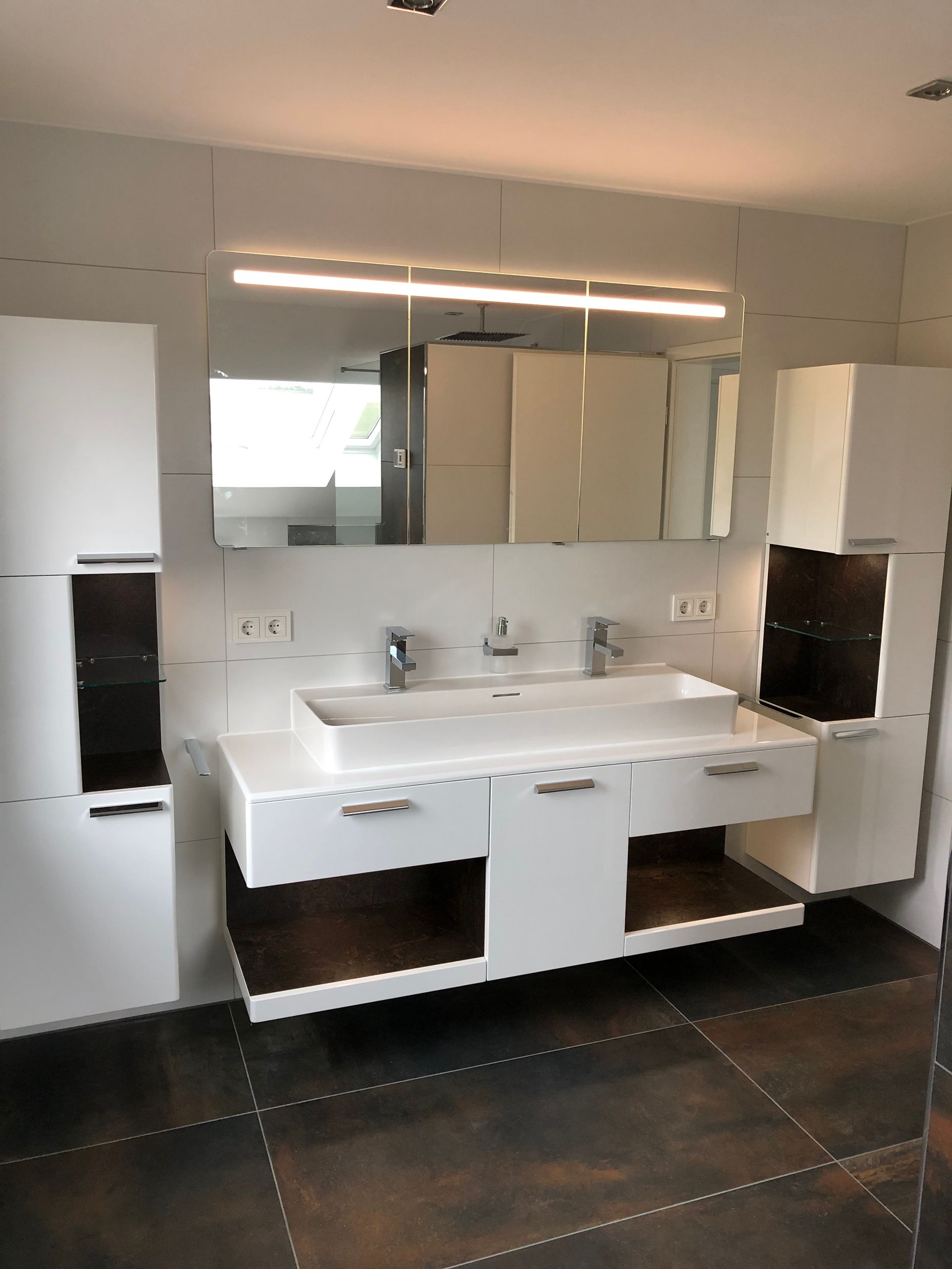 Modernes weißes Badezimmer mit Doppelwaschbecken, Spiegel und Aufbewahrungsschränken.