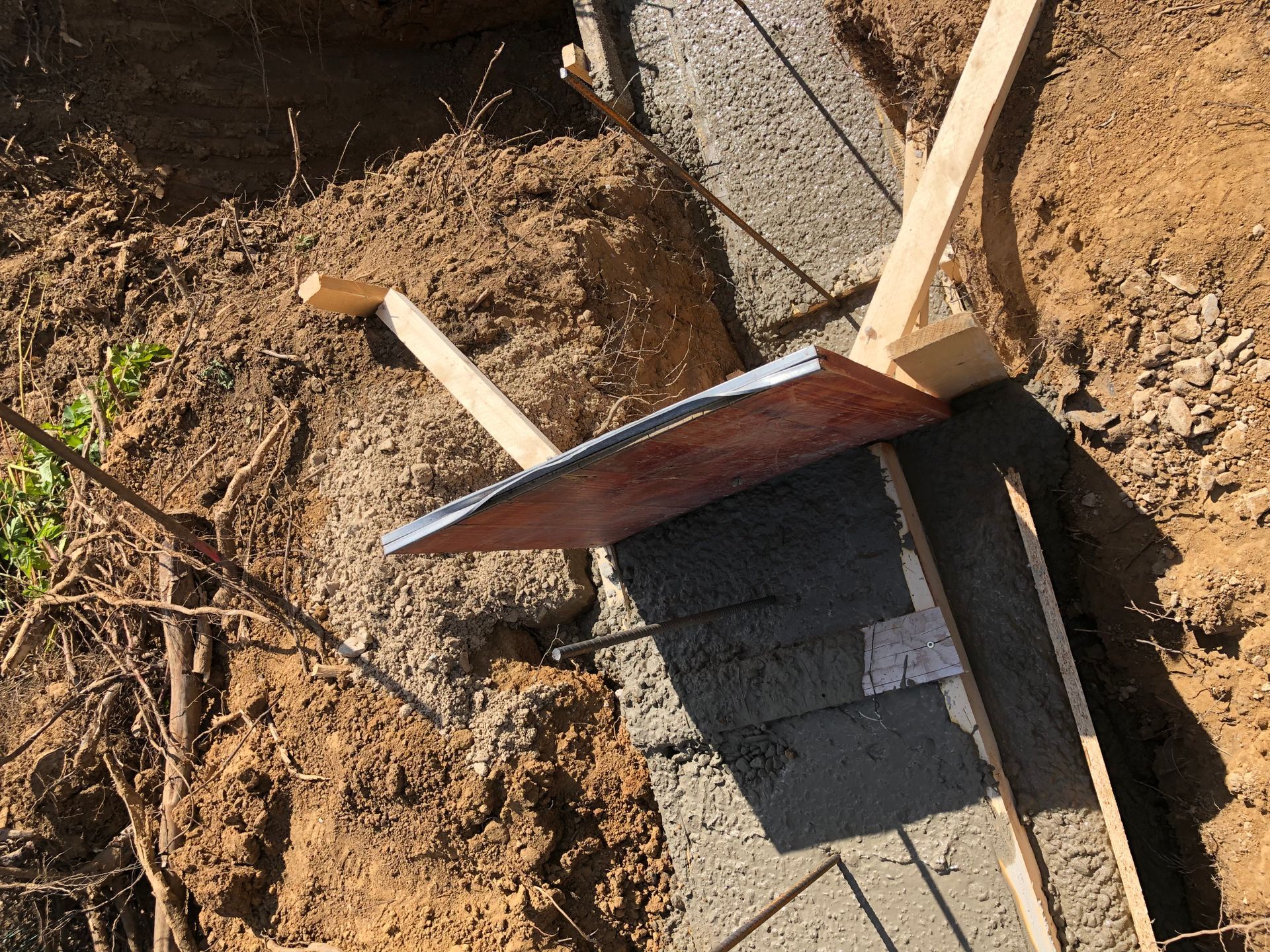 Frischbetonkonstruktion mit einem Nivellierwerkzeug im Einsatz, Einstellung in einer Außenumgebung aus Erde.