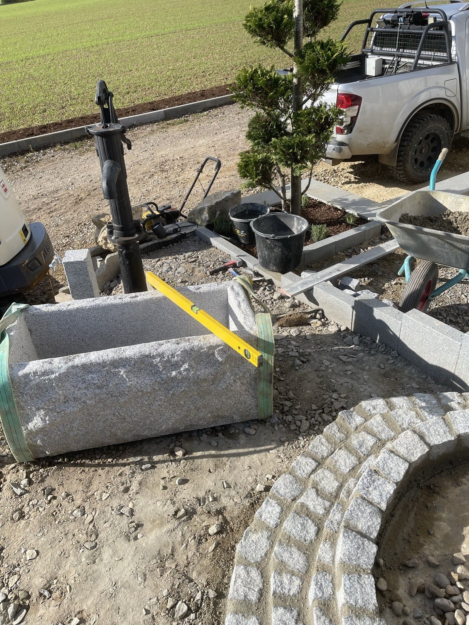Granitbecken, Ebene und Landschaftsgestaltung im Gange, neben einem kleinen Baum und einem Pickup.