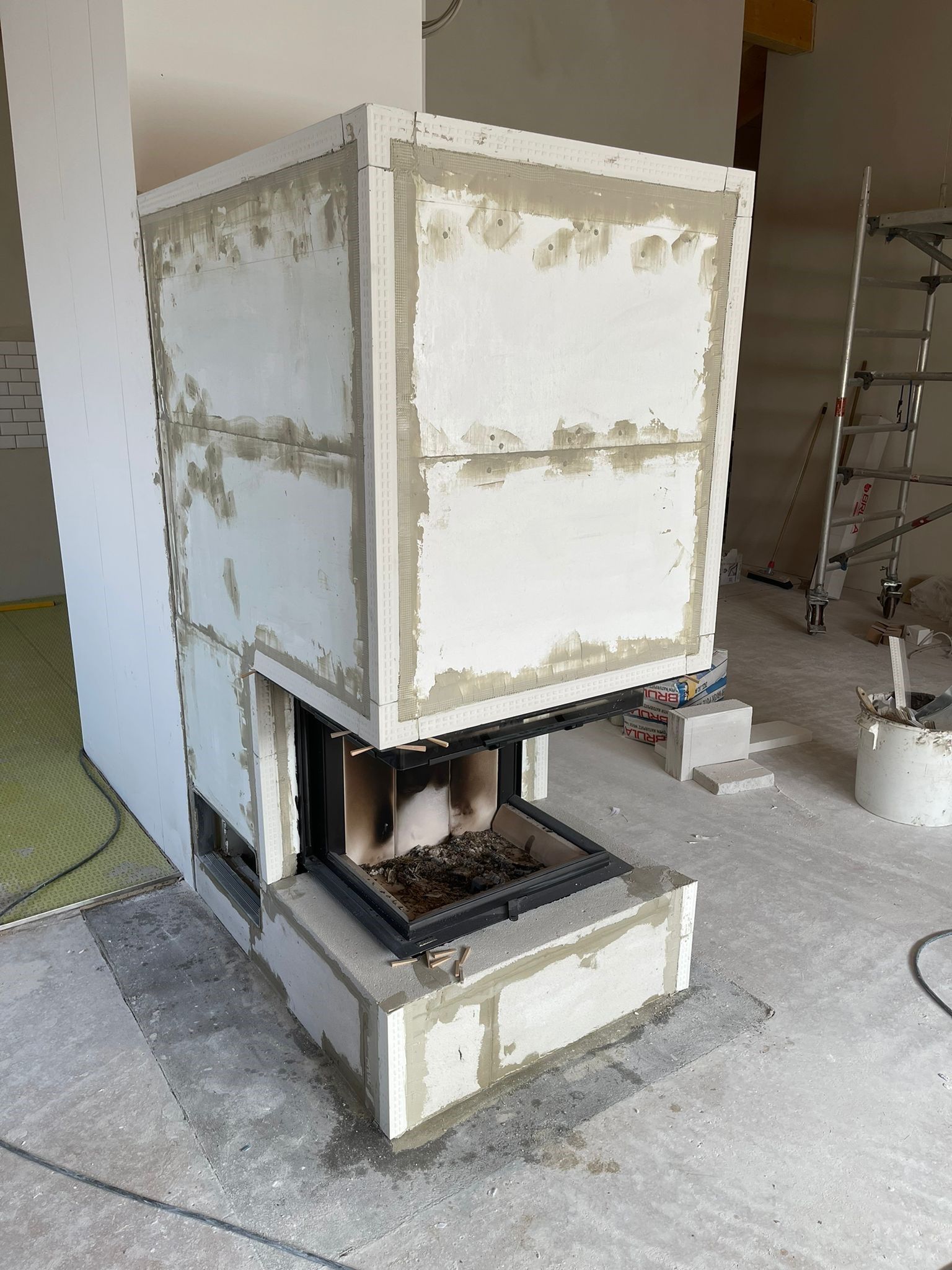 Kamin im Bau; weißer Ziegel mit Mörtel, unfertiger Innenraum.
