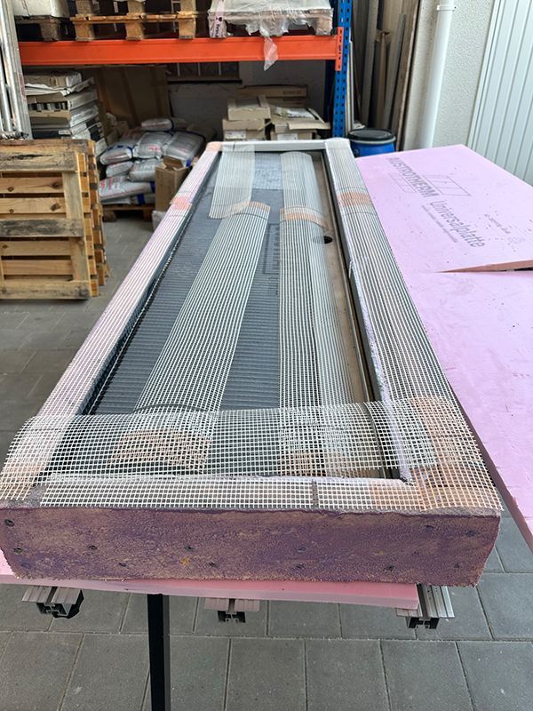 Türrahmen, umwickelt mit Netz und rosa Isolierung, auf einem Tisch liegend.