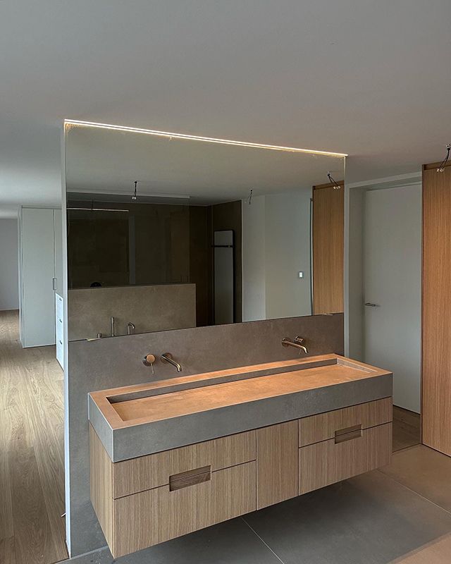 Modernes Badezimmer mit schwebendem Holzwaschtisch, Betonwaschbecken, großem Spiegel und neutralen Farbtönen.