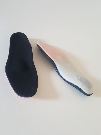 Deux semelles orthopédiques, l'une et l'autre dessus, sur une surface.