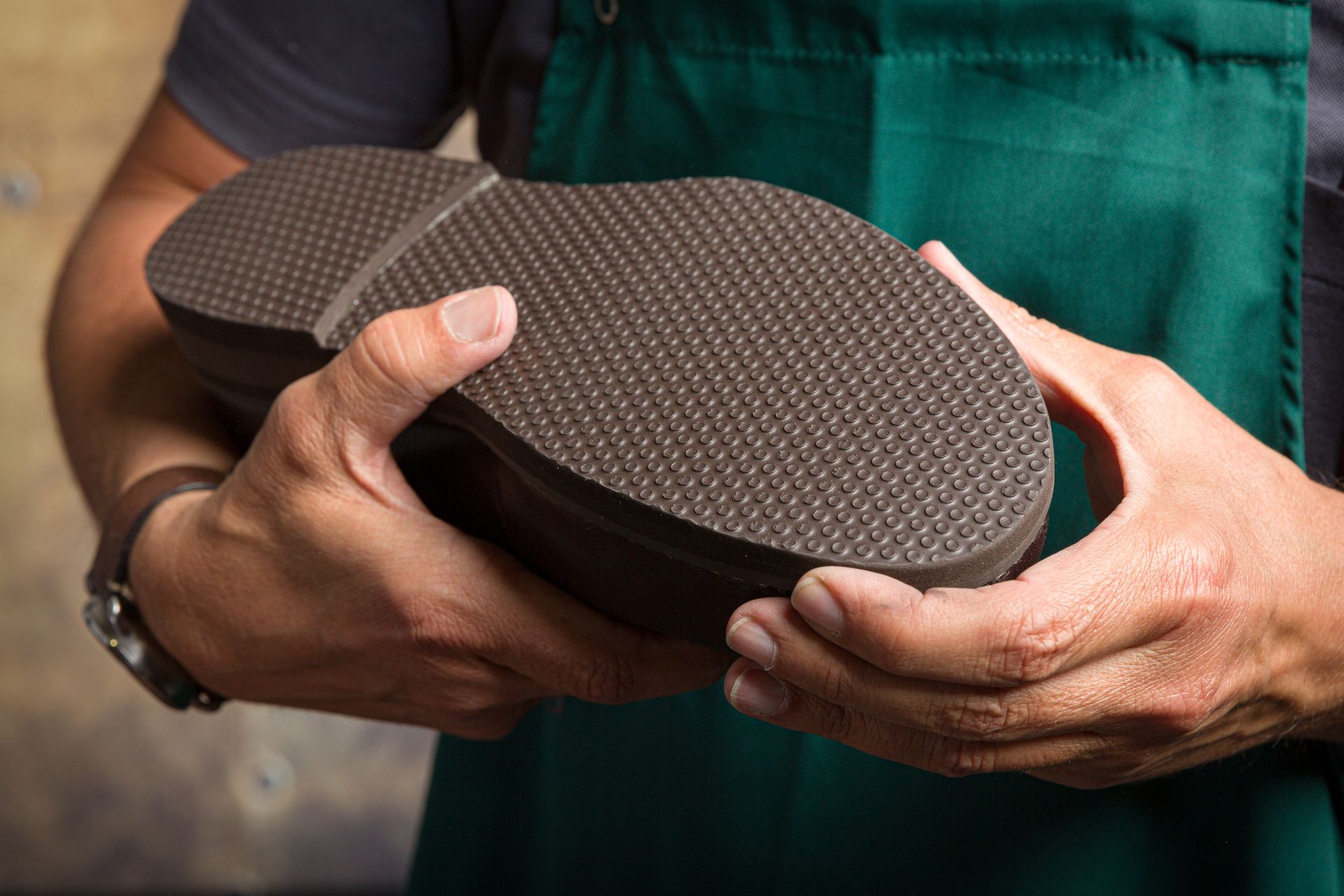 Des mains tenant une chaussure texturée contre un tablier.