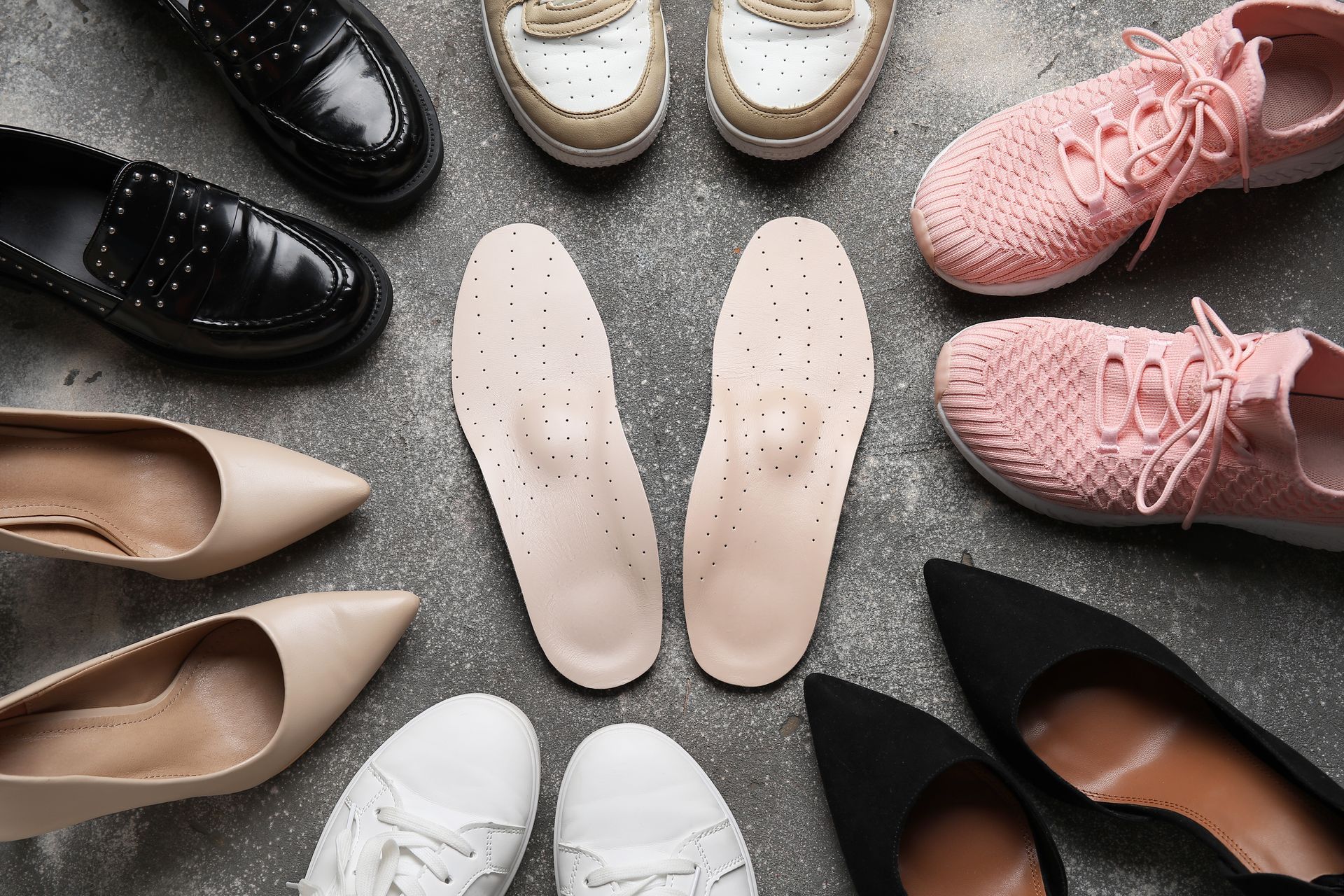 Des chaussures assorties, de couleurs et de styles variés, sont disposées en cercle sur une surface.