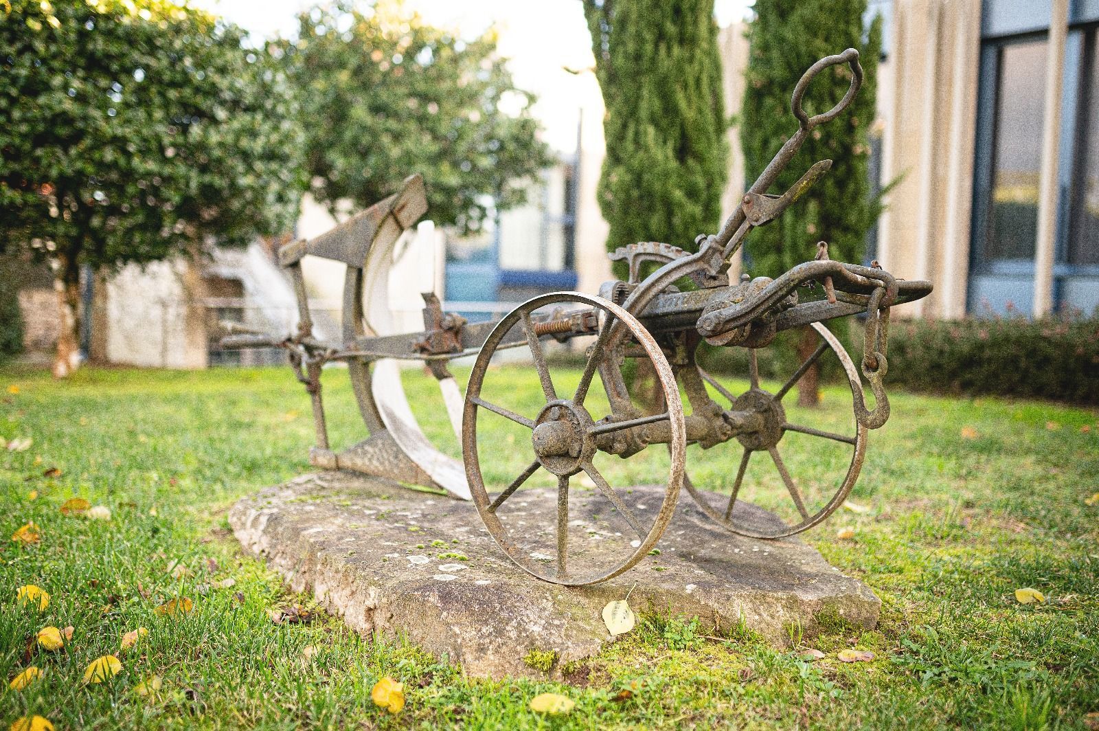 Un arado viejo está sentado encima de una roca en la hierba.