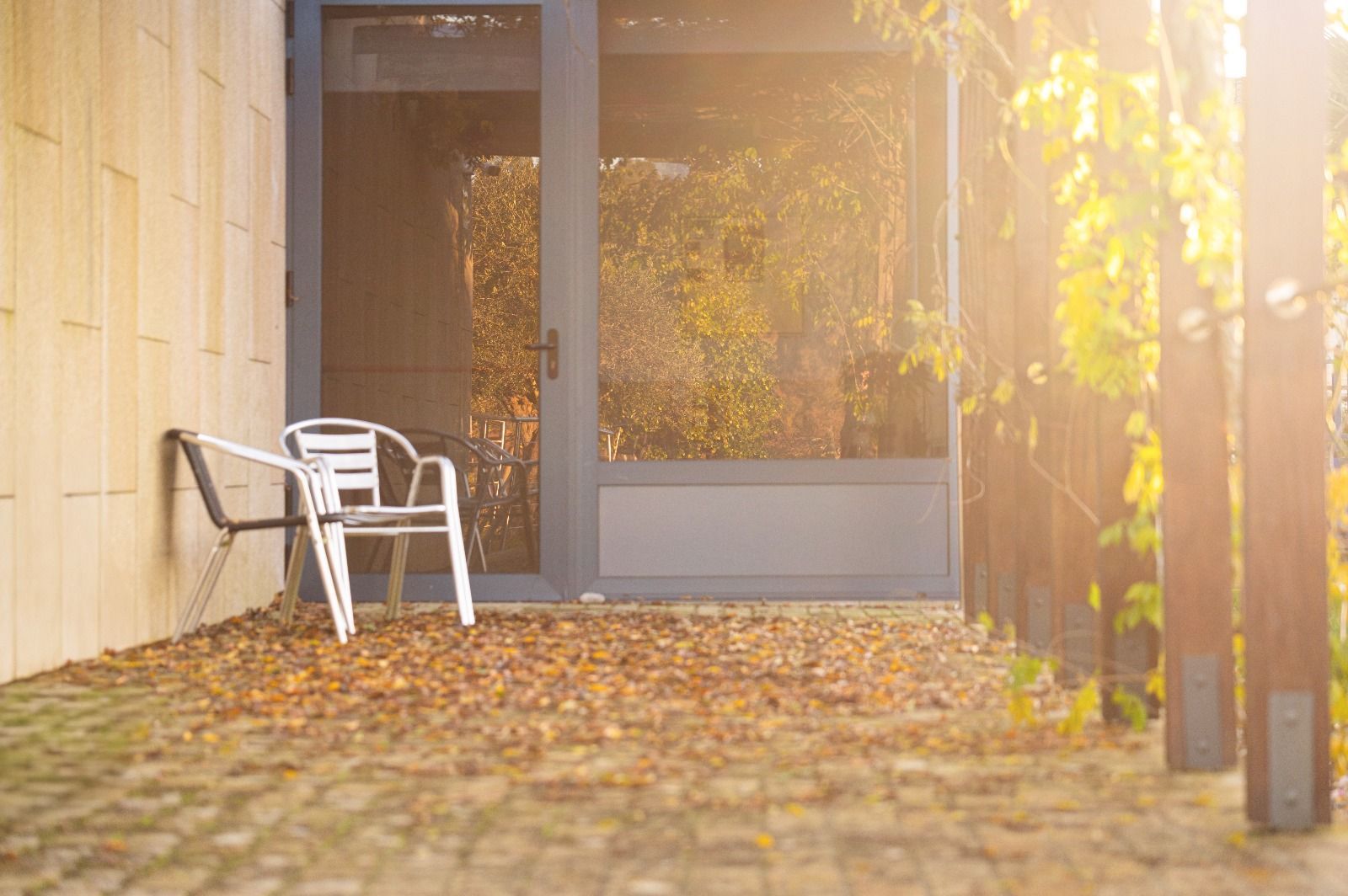 Una silla blanca está sentada en un patio al lado de una puerta.