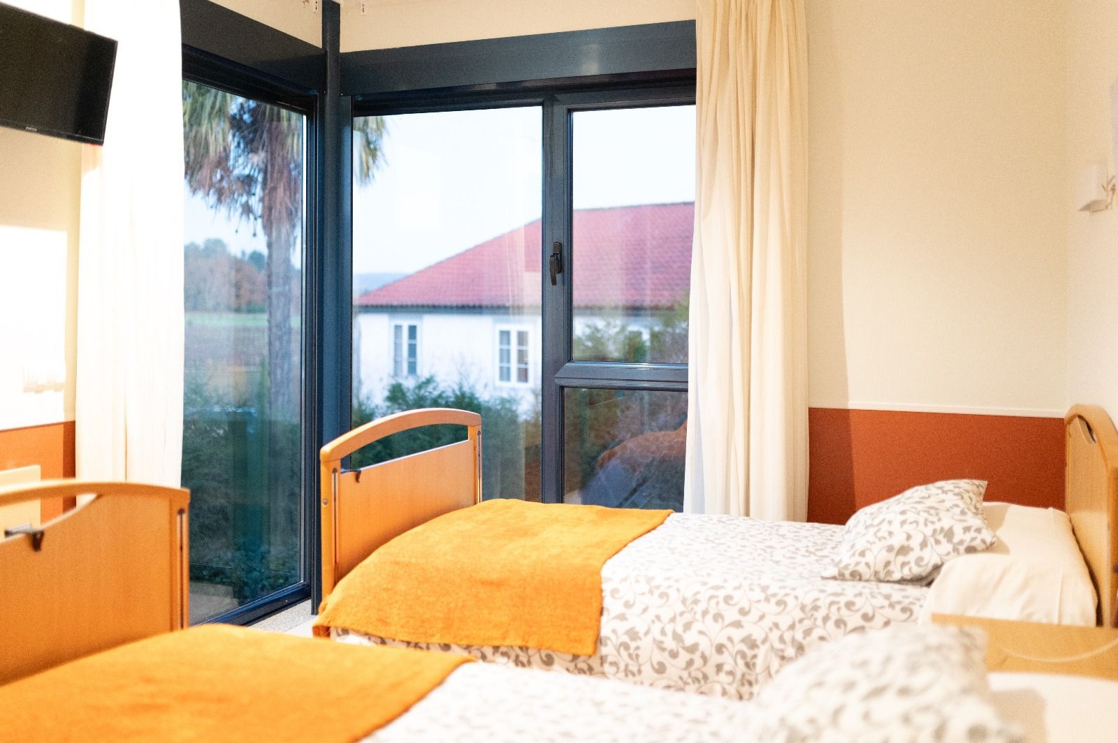 Una habitación de hospital con dos camas y una ventana grande.