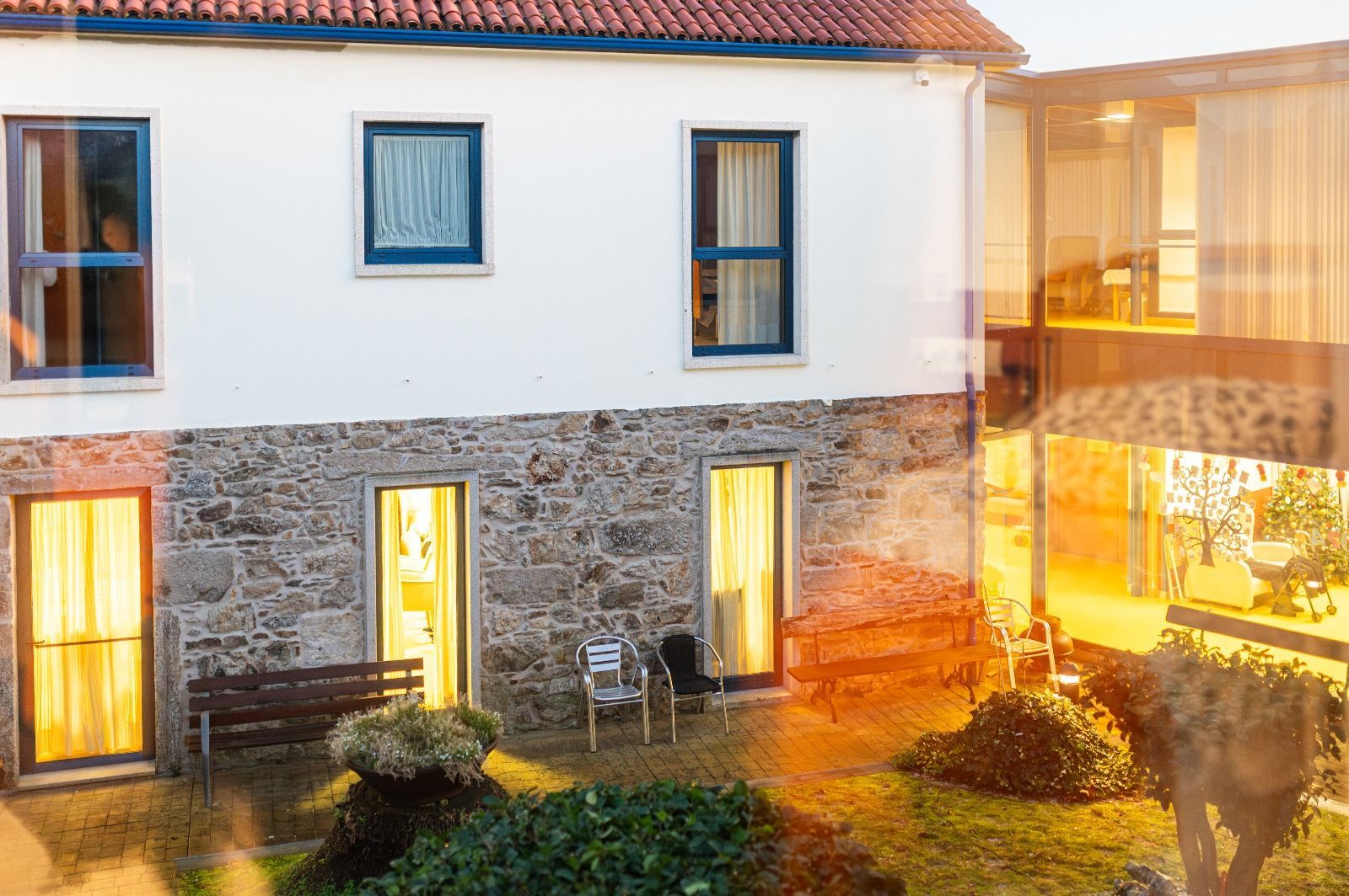 Una gran casa blanca con muchas ventanas y un banco delante de ella.