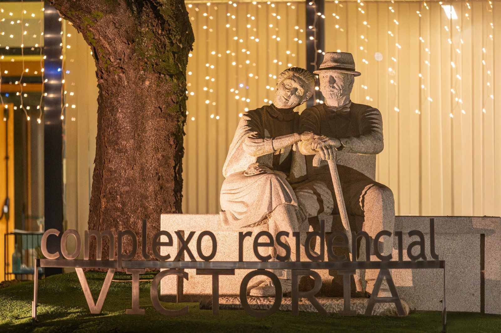 Una estatua de un hombre y una mujer sentados en un banco frente a un edificio.