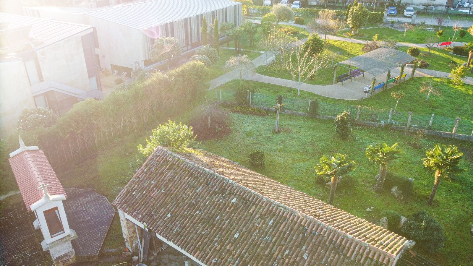 Una vista aérea de una casa con techo rodeado de árboles y césped.